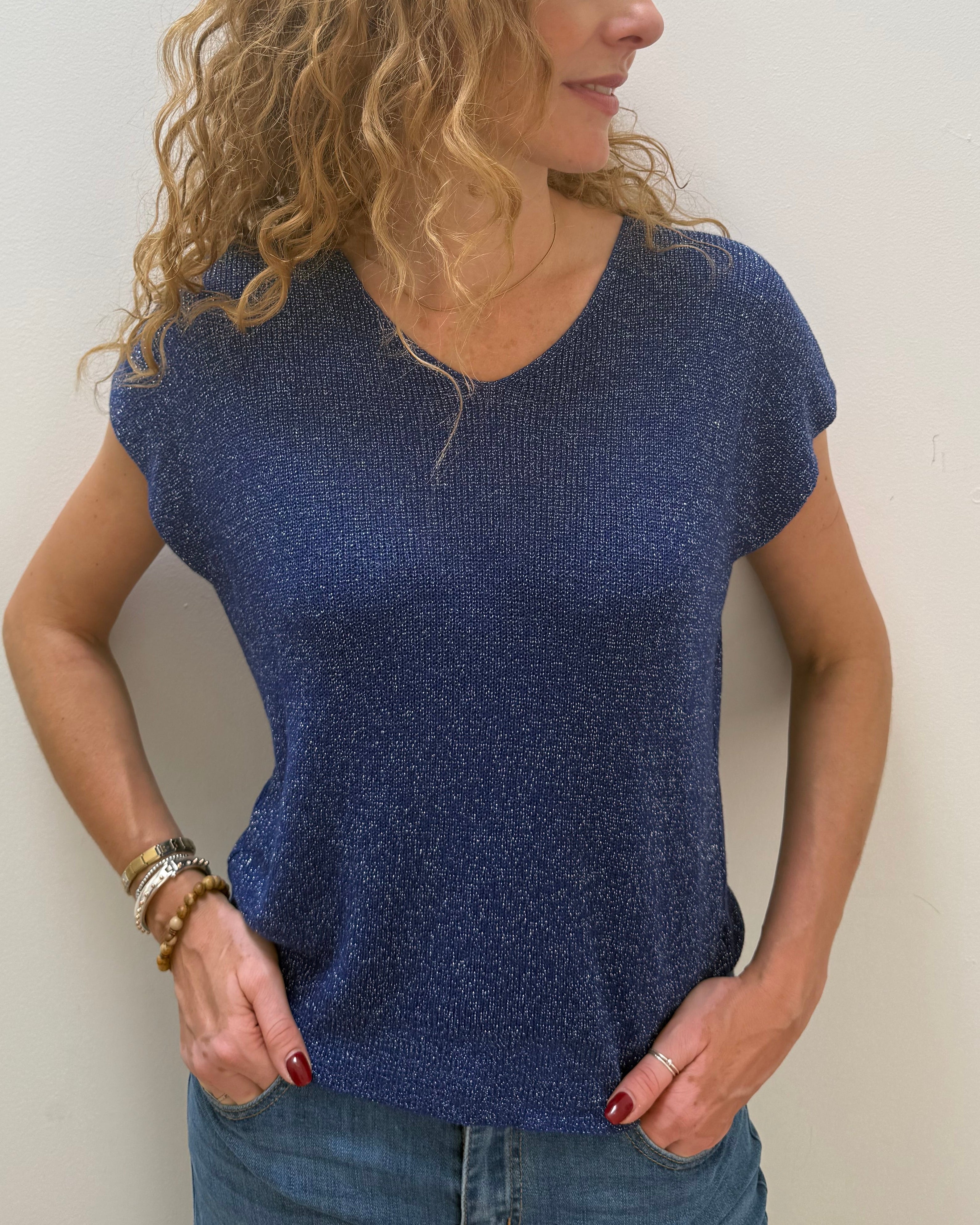 Woman wearing a blue top and jeans against a white background