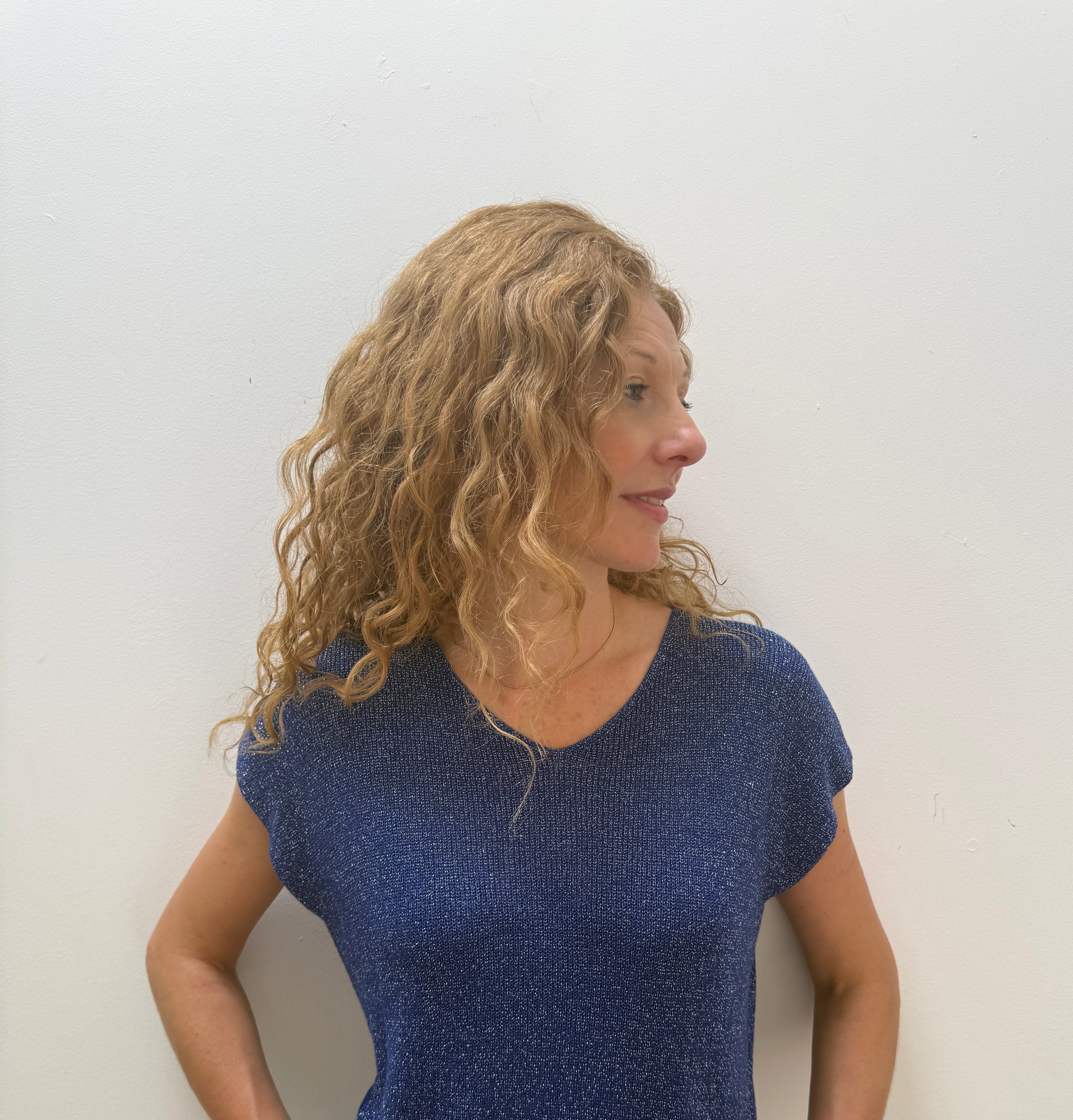 Woman wearing a blue top and jeans against a white background