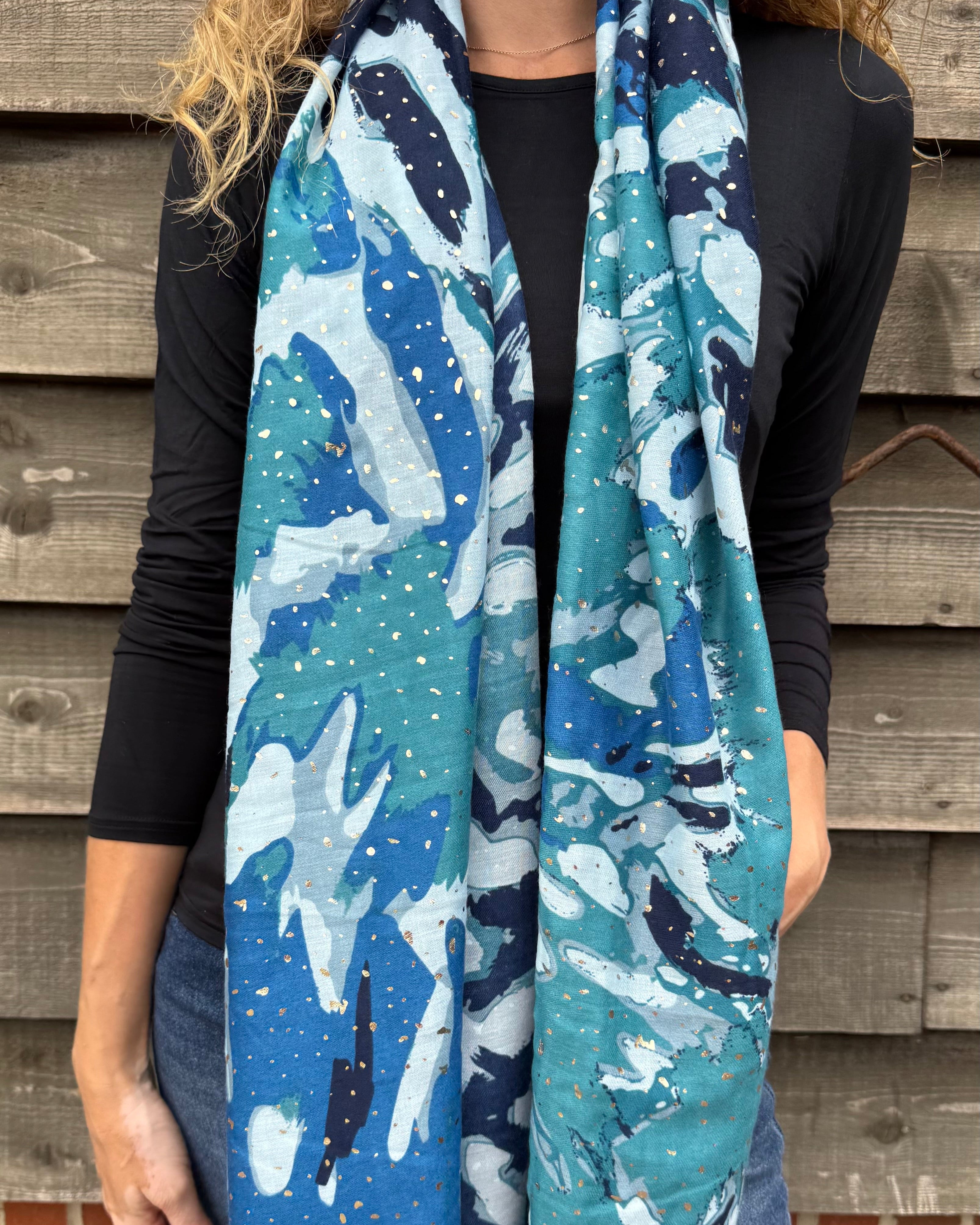 Person wearing a blue and white patterned scarf against a wooden wall.