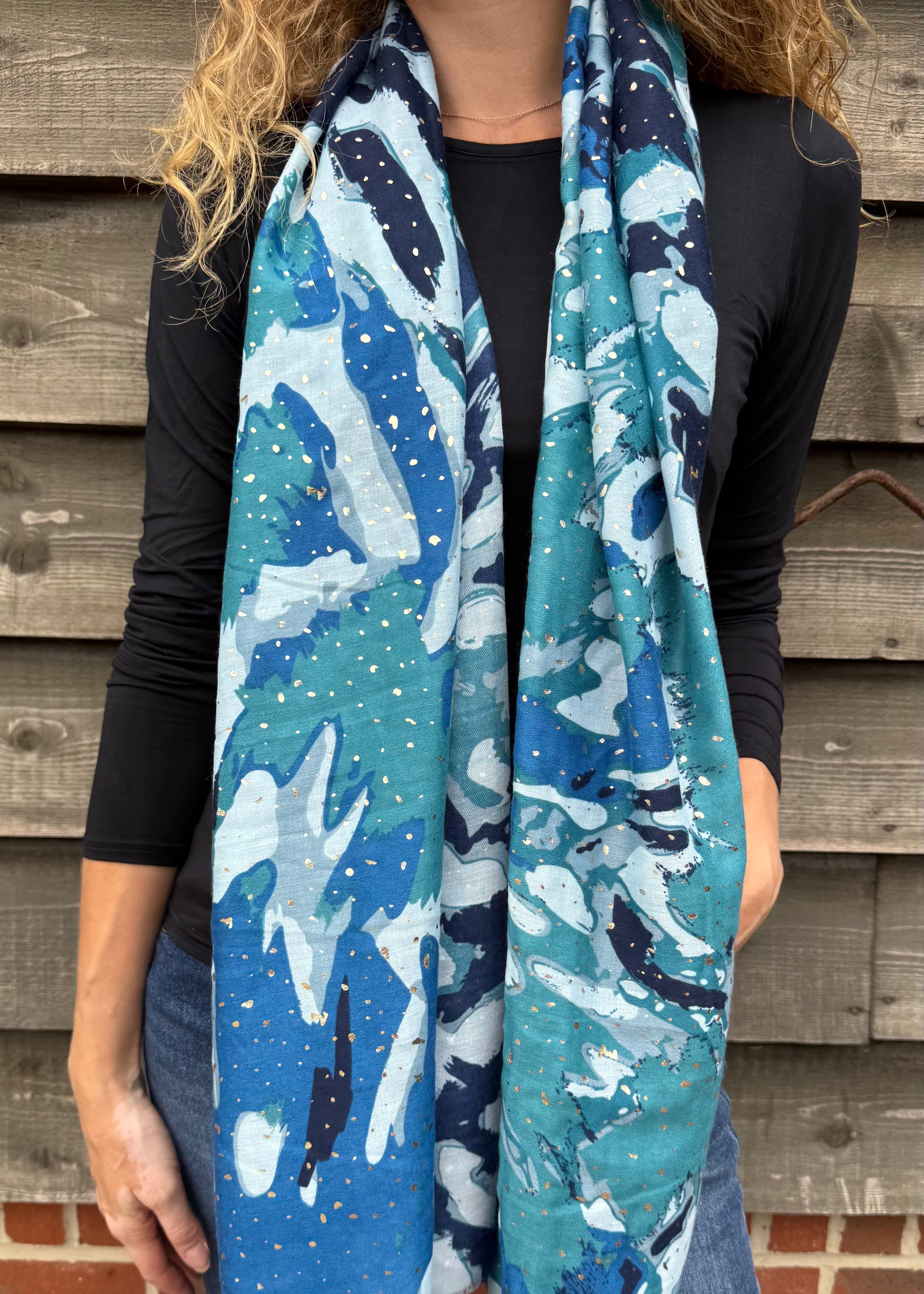 Person wearing a blue and white patterned scarf against a wooden wall.