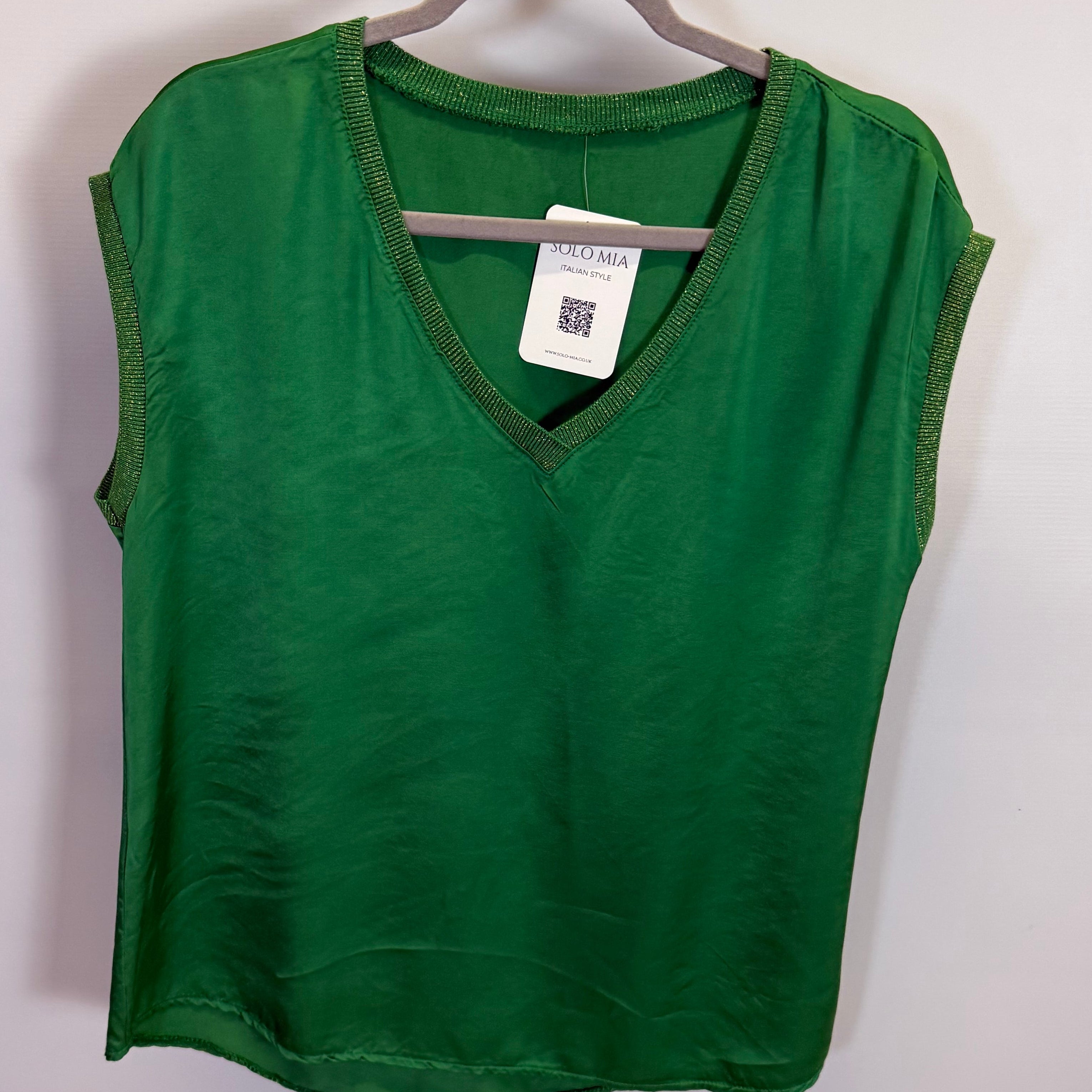 Green t-shirt on a hanger against a plain background