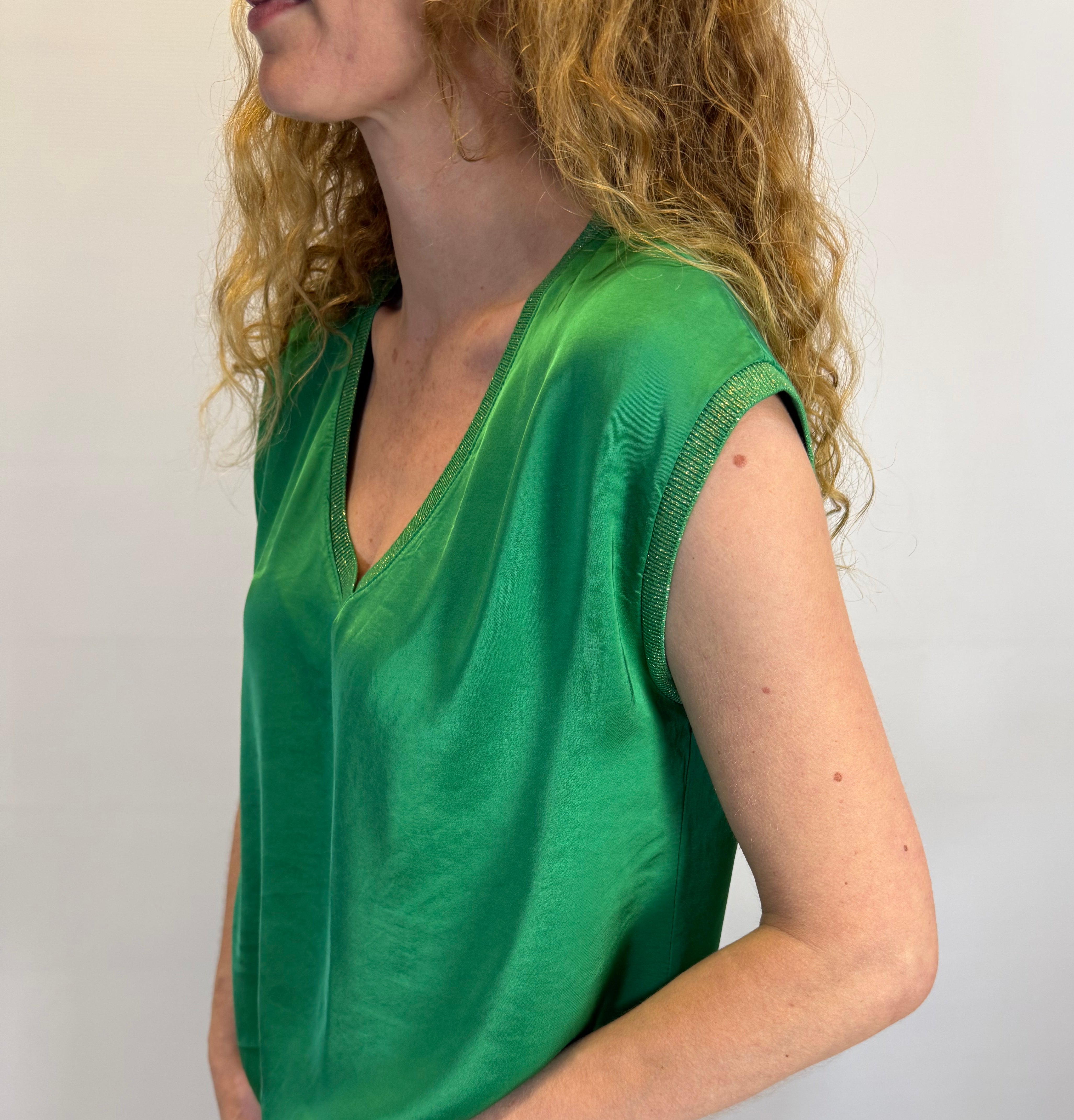 Person wearing a green top and blue jeans on a plain background