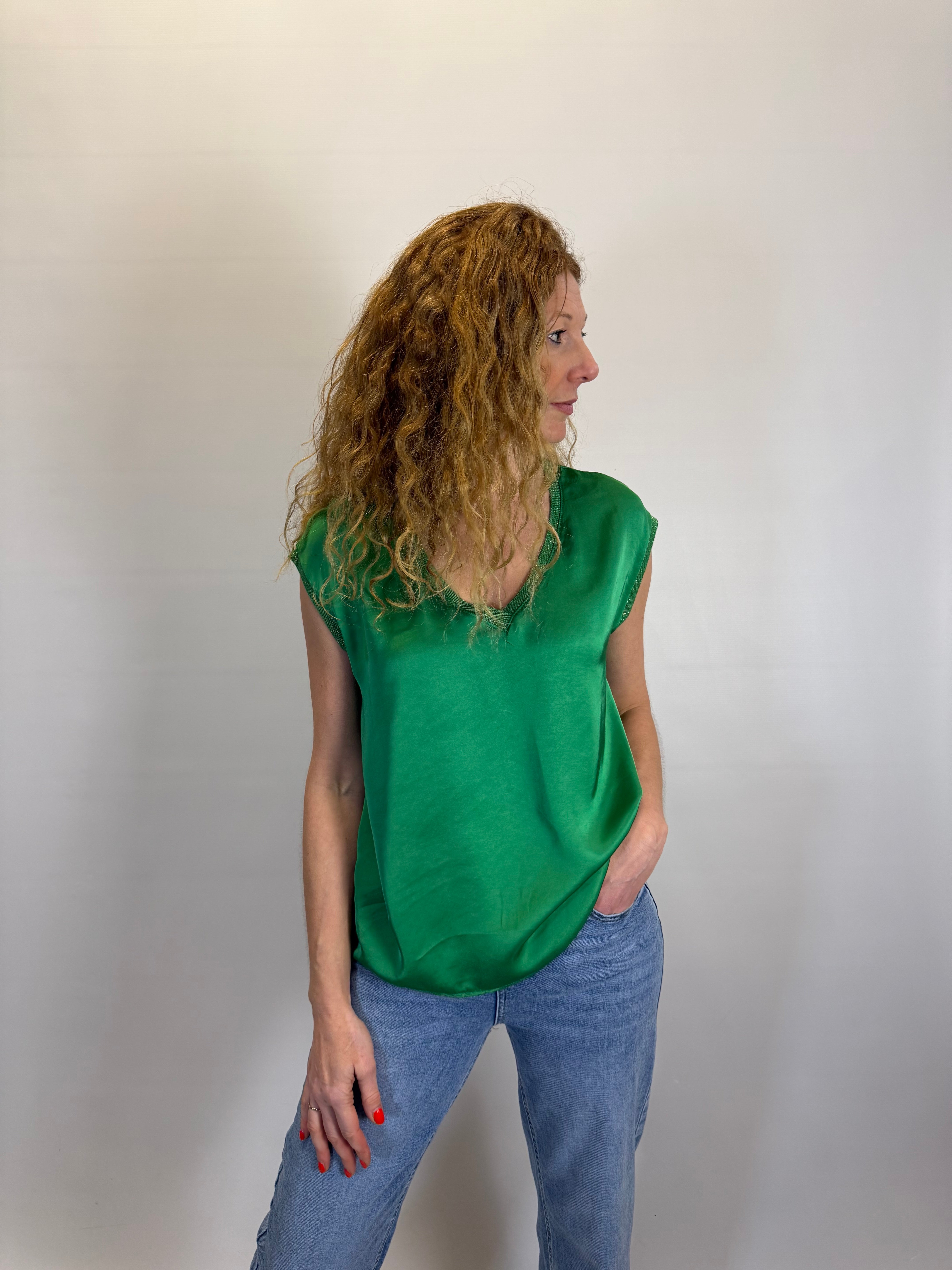 Person wearing a green top and blue pants on a plain background