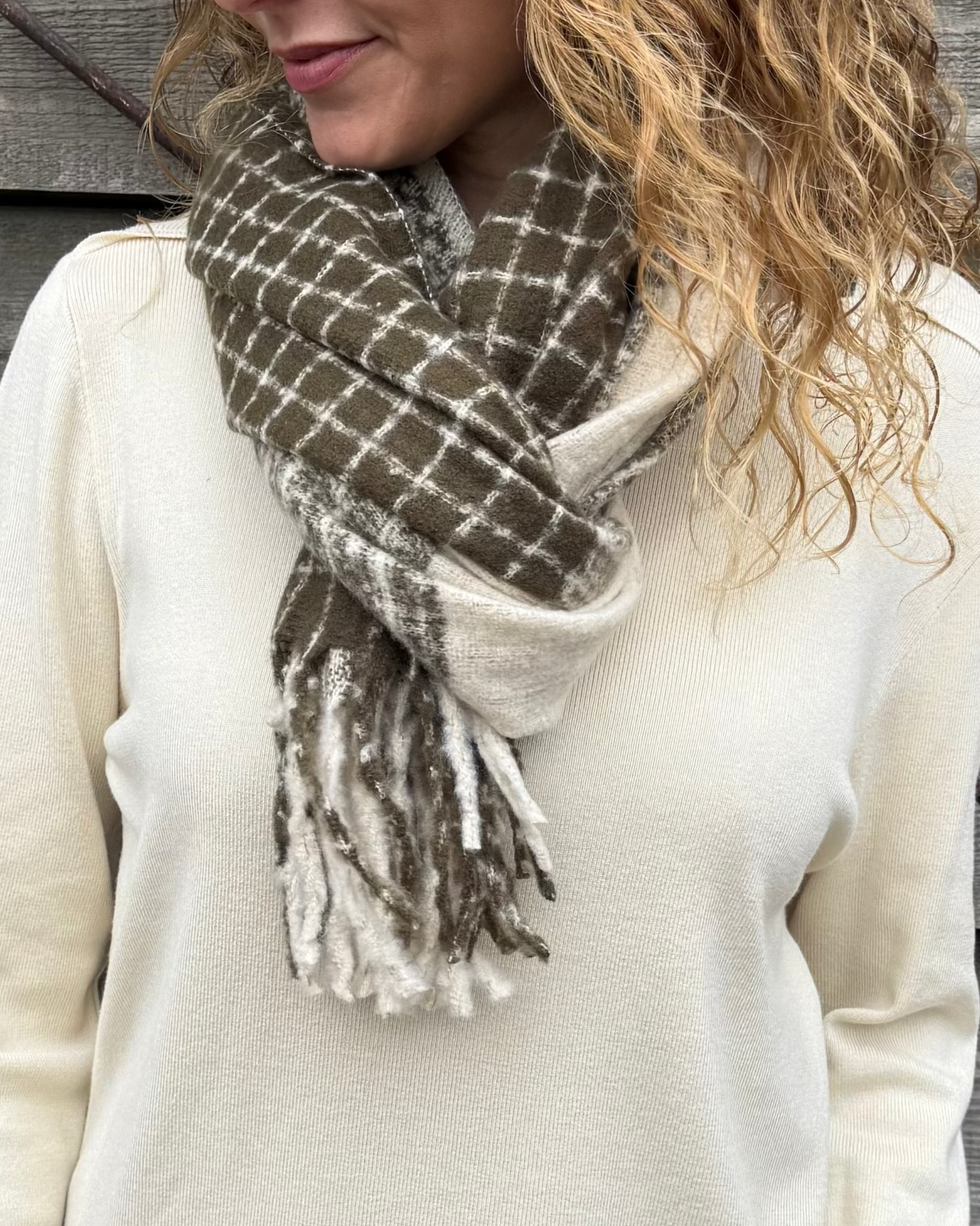 Woman wearing a plaid scarf against a wooden wall