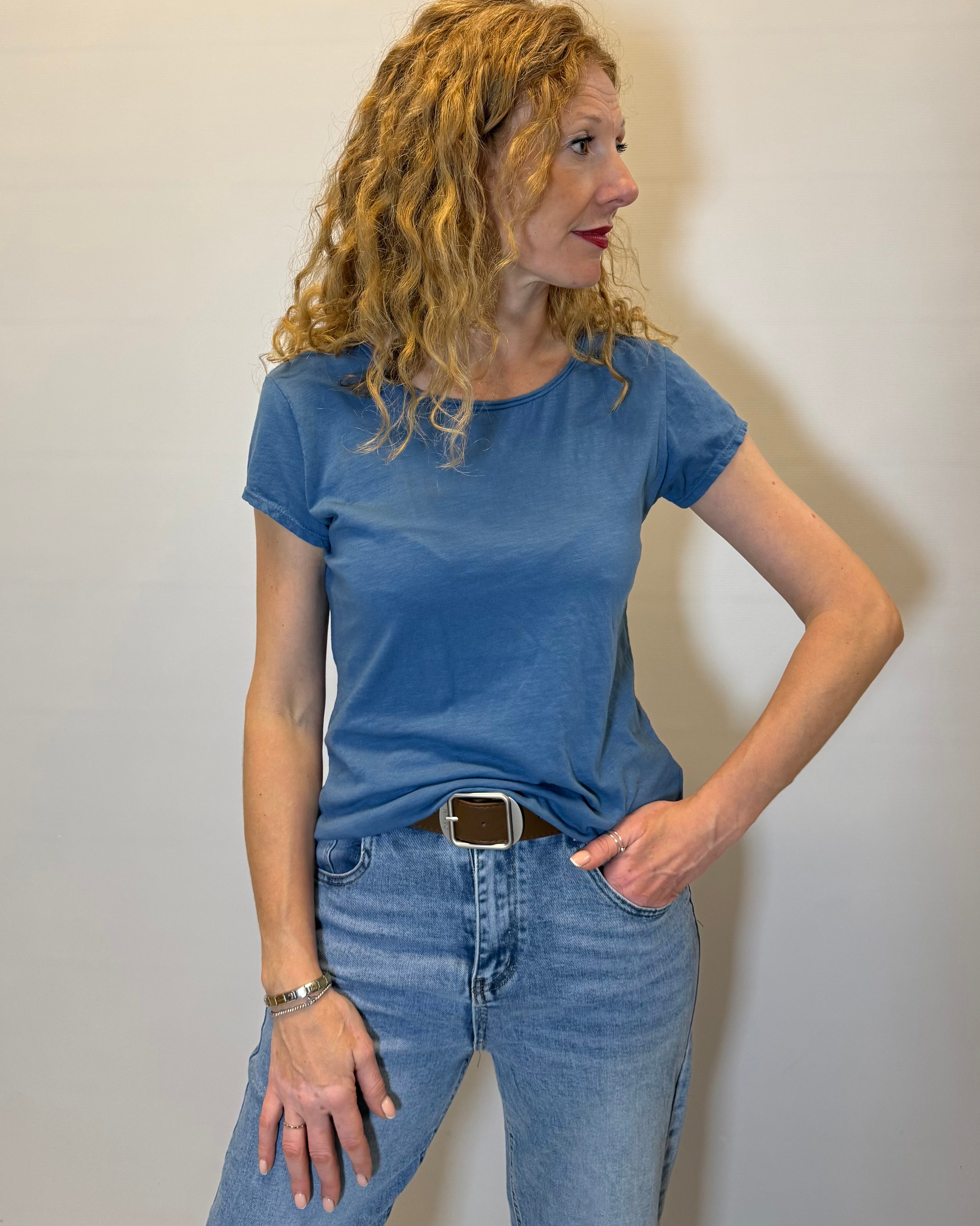 Woman wearing a blue t-shirt and jeans against a plain background