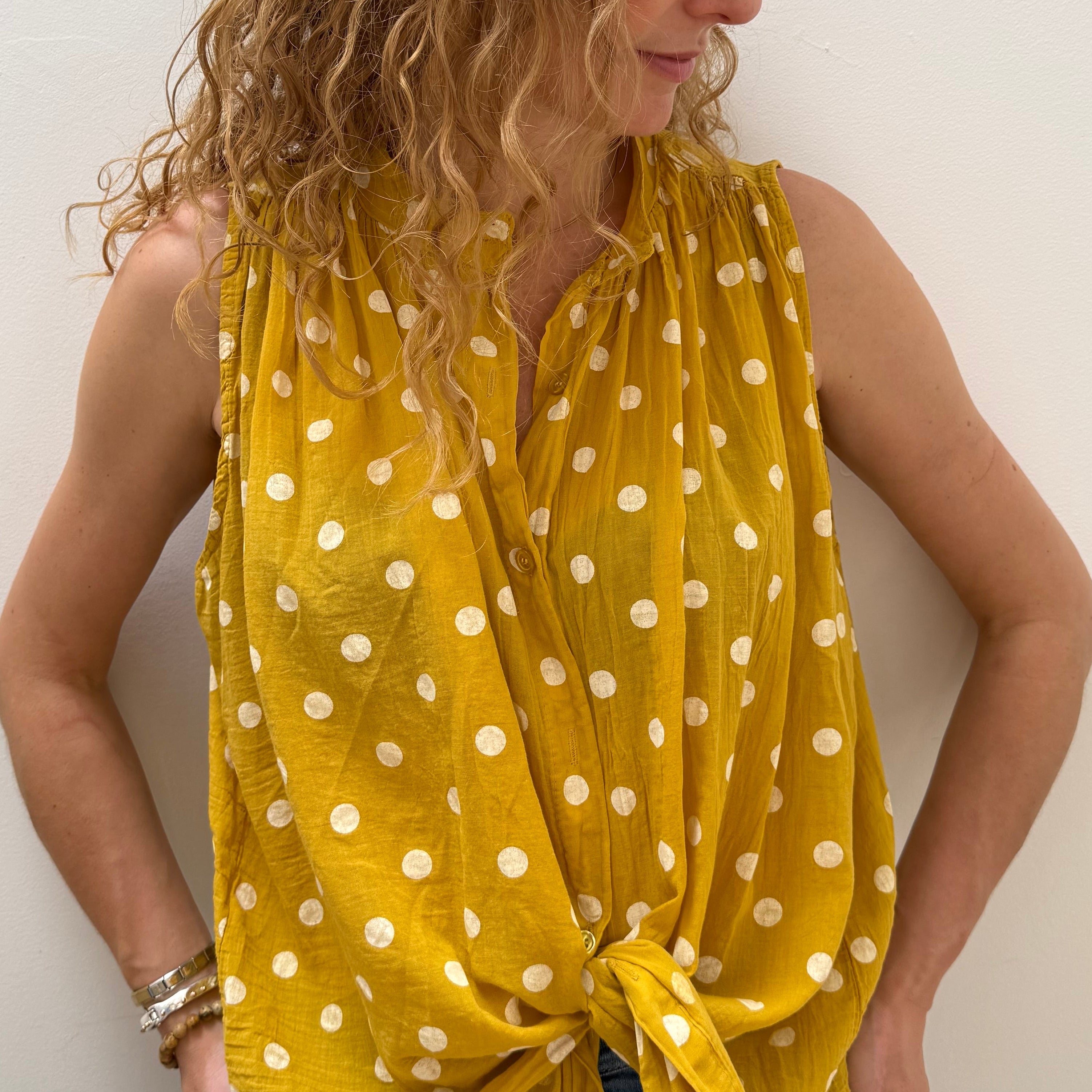 Woman wearing a yellow polka dot dress on a white background