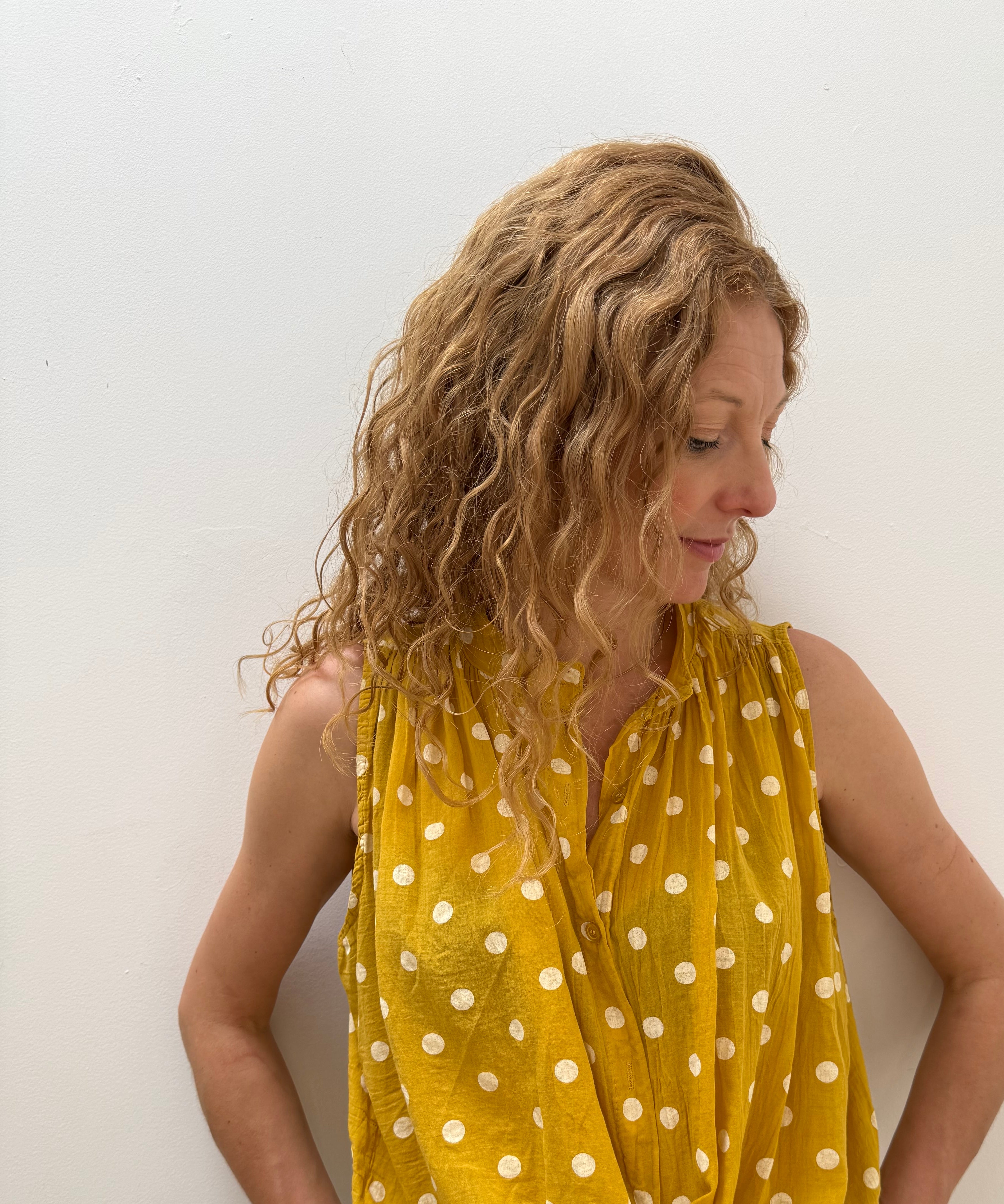 Woman wearing a yellow polka dot dress on a white background
