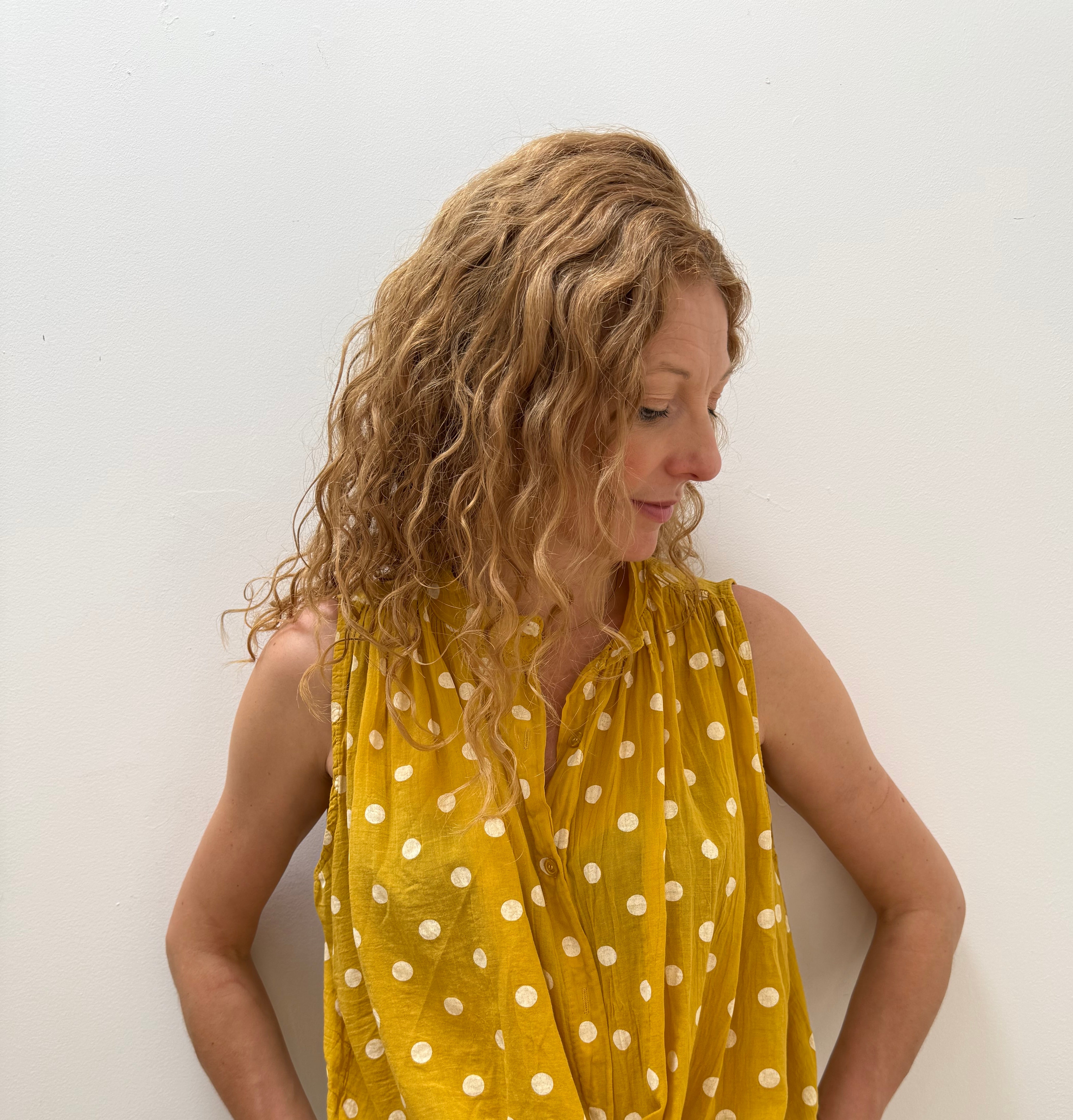Woman wearing a yellow polka dot dress on a white background