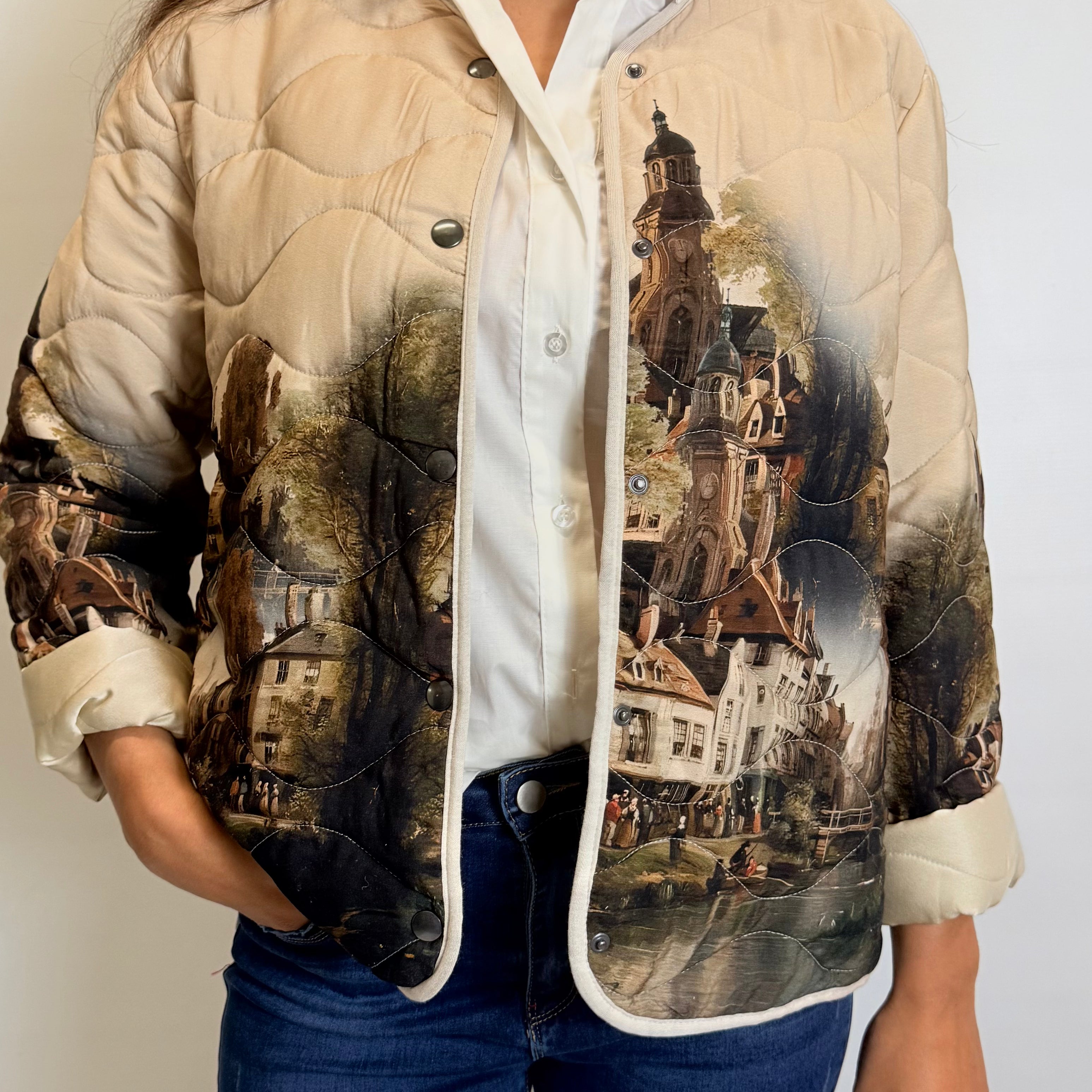 Person wearing a beige quilted jacket with vintage-style cityscape print