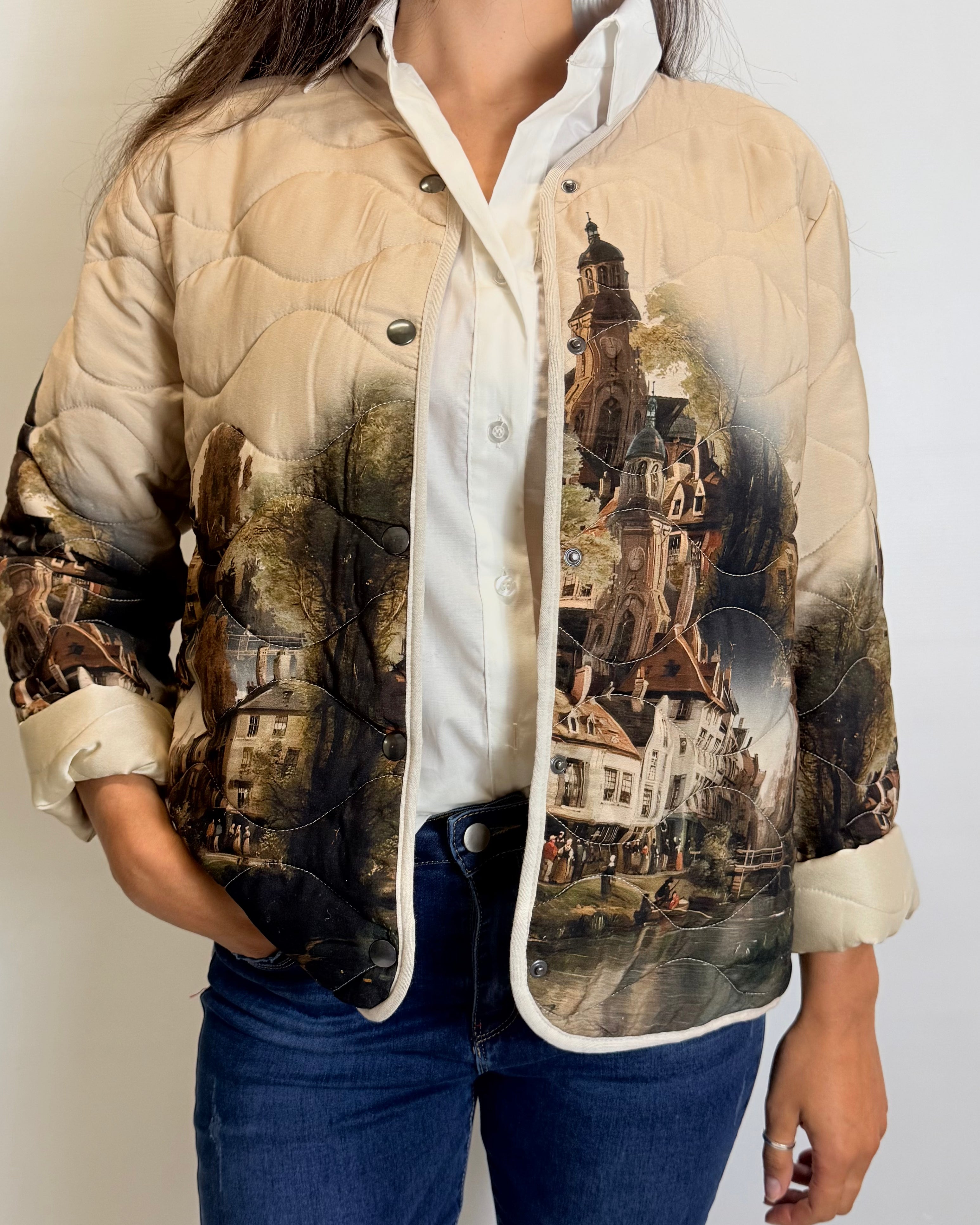 Person wearing a beige quilted jacket with vintage-style cityscape print