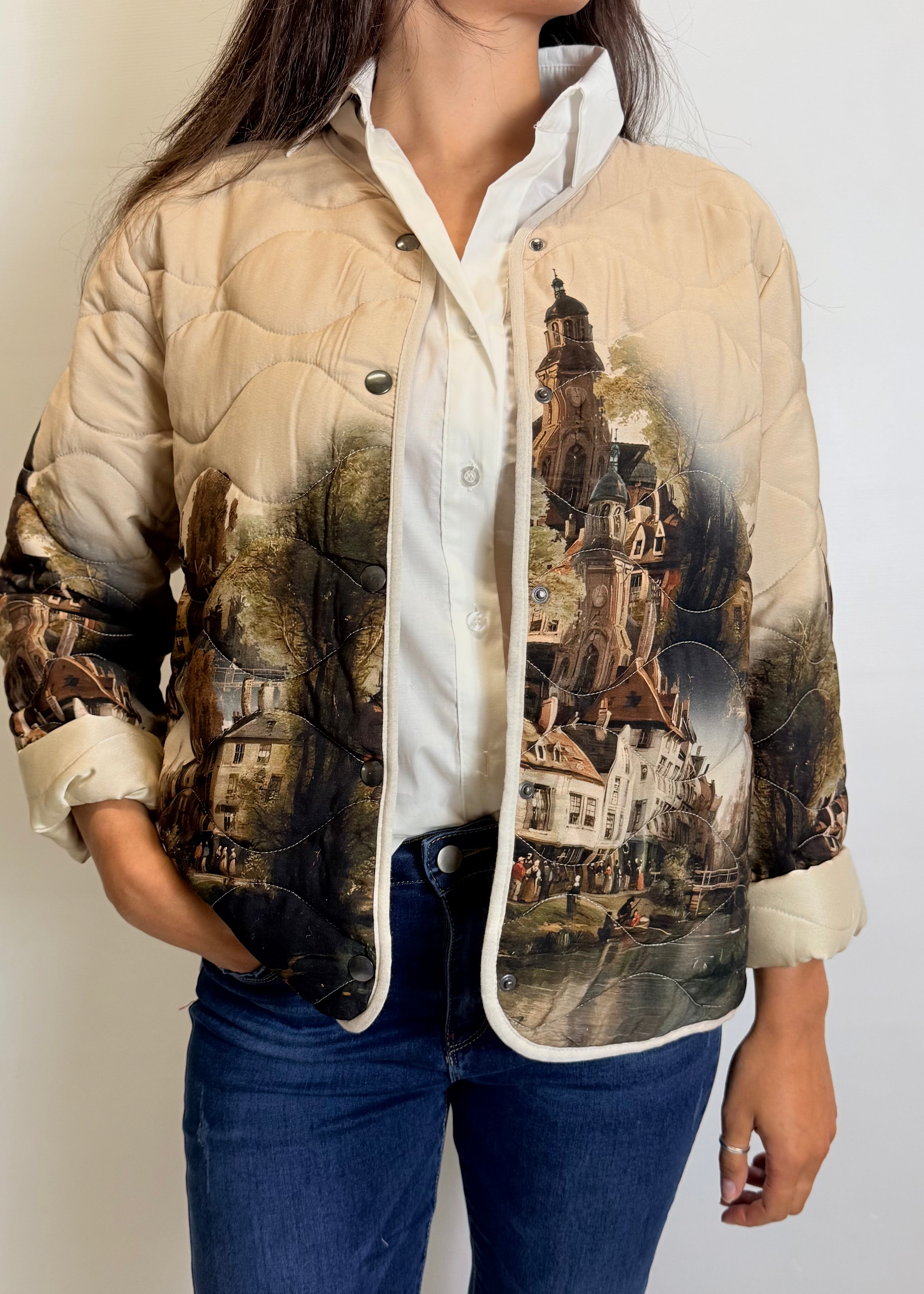 Person wearing a beige quilted jacket with vintage-style cityscape print