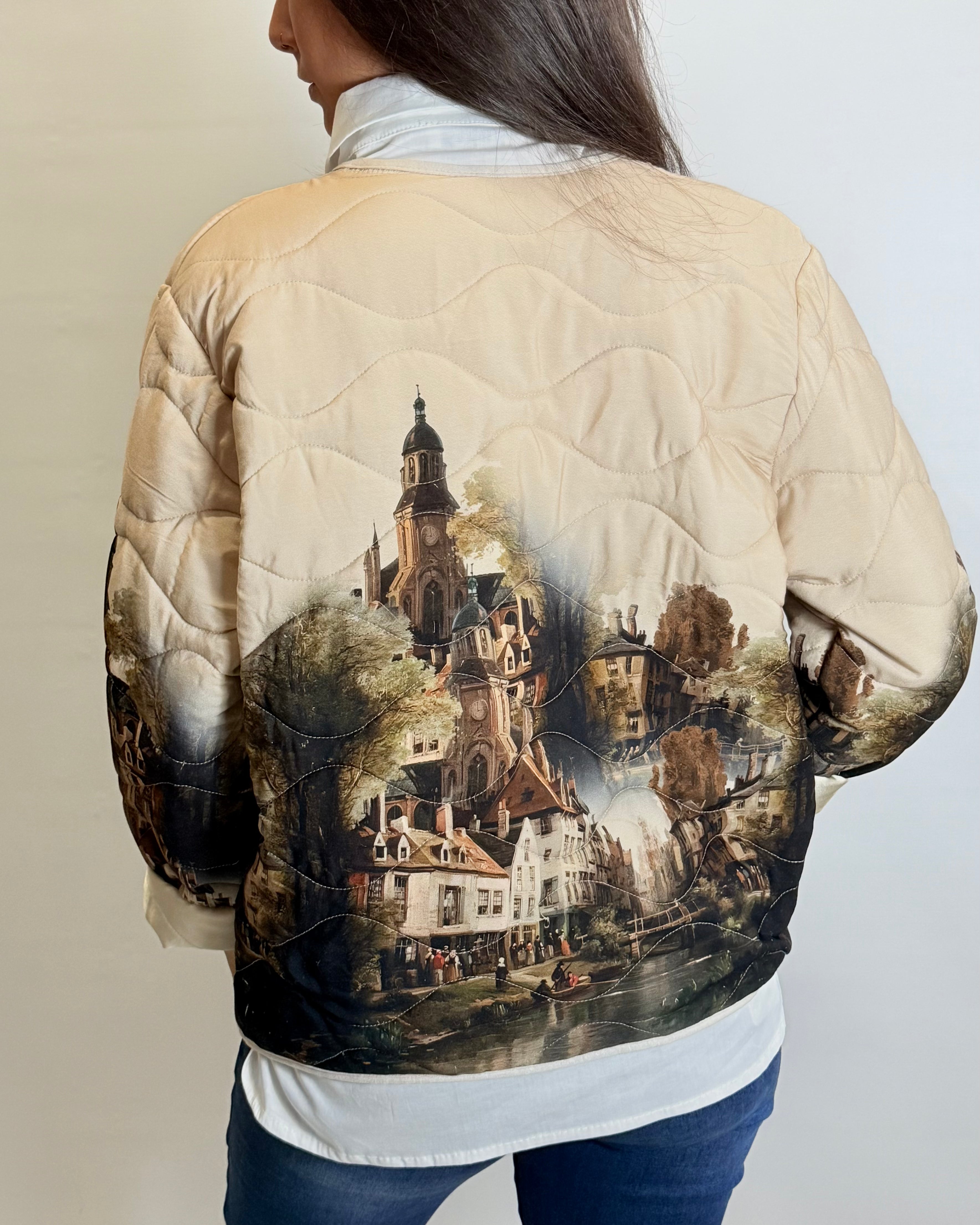 Person wearing a beige quilted jacket with a scenic print on the back