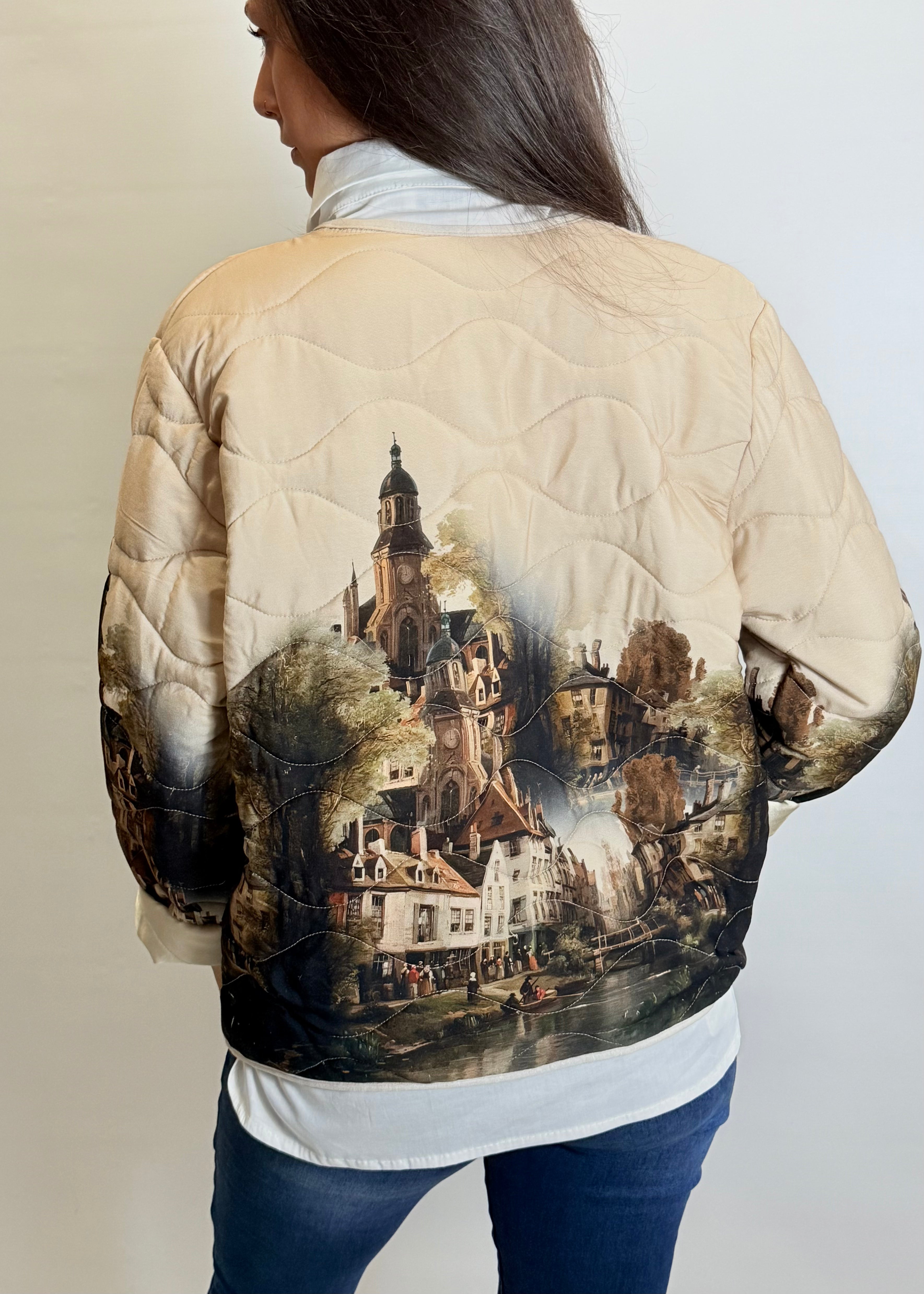Person wearing a beige quilted jacket with a scenic print on the back