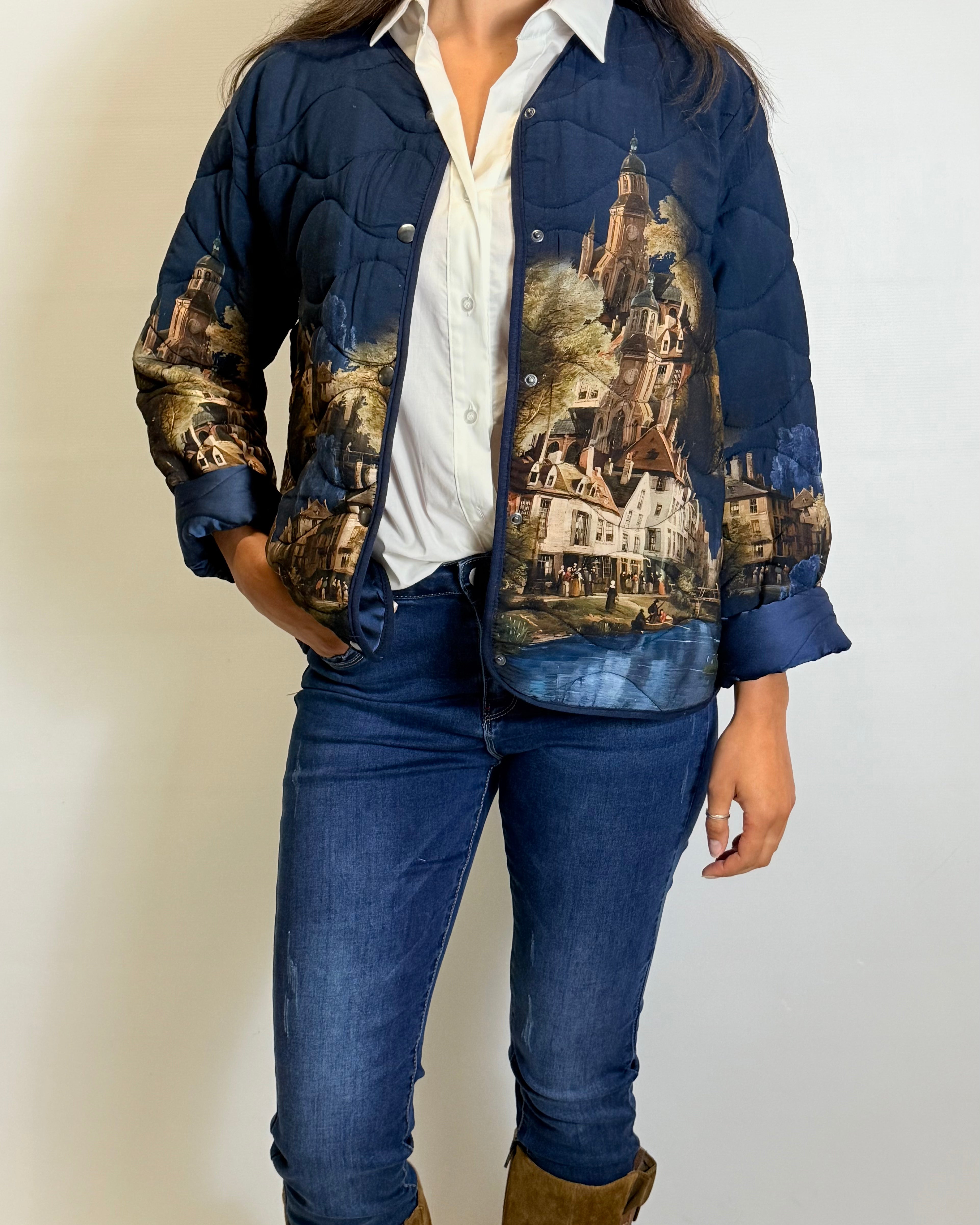 Person wearing a blue jacket with artistic designs, white shirt, blue jeans, and brown boots on a plain background