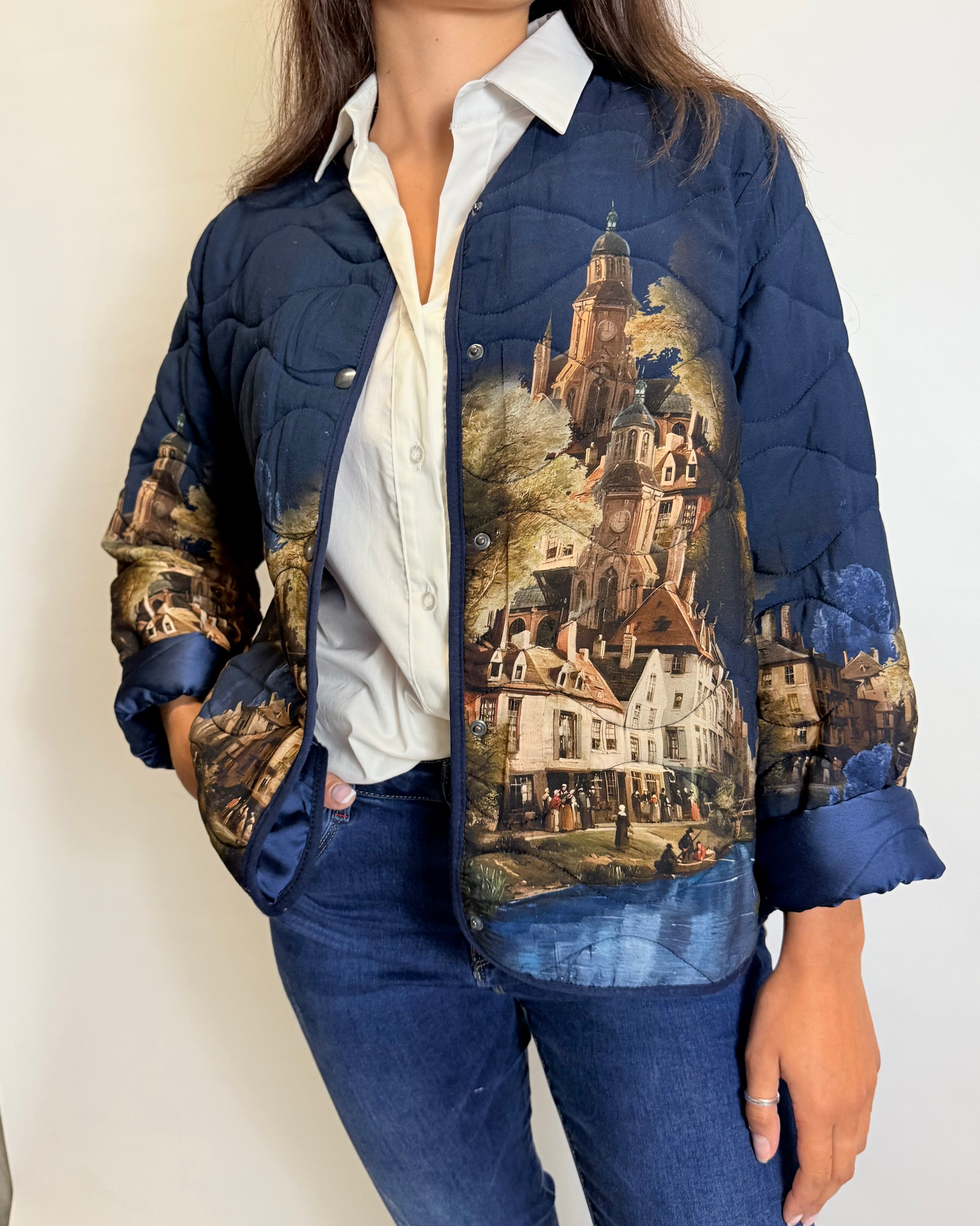 Person wearing a blue quilted jacket with a scenic print on a plain background