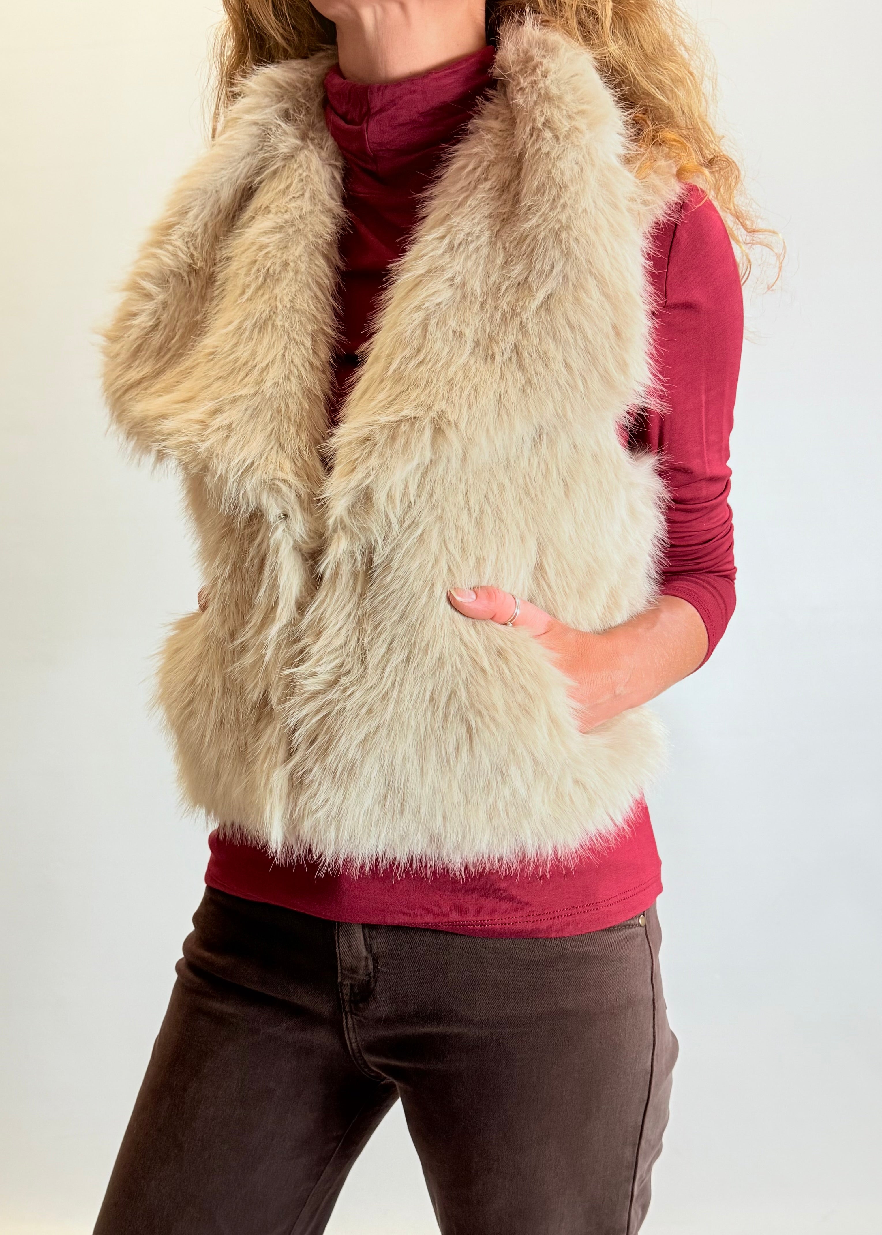 Person wearing a fur vest over a red shirt on a white background