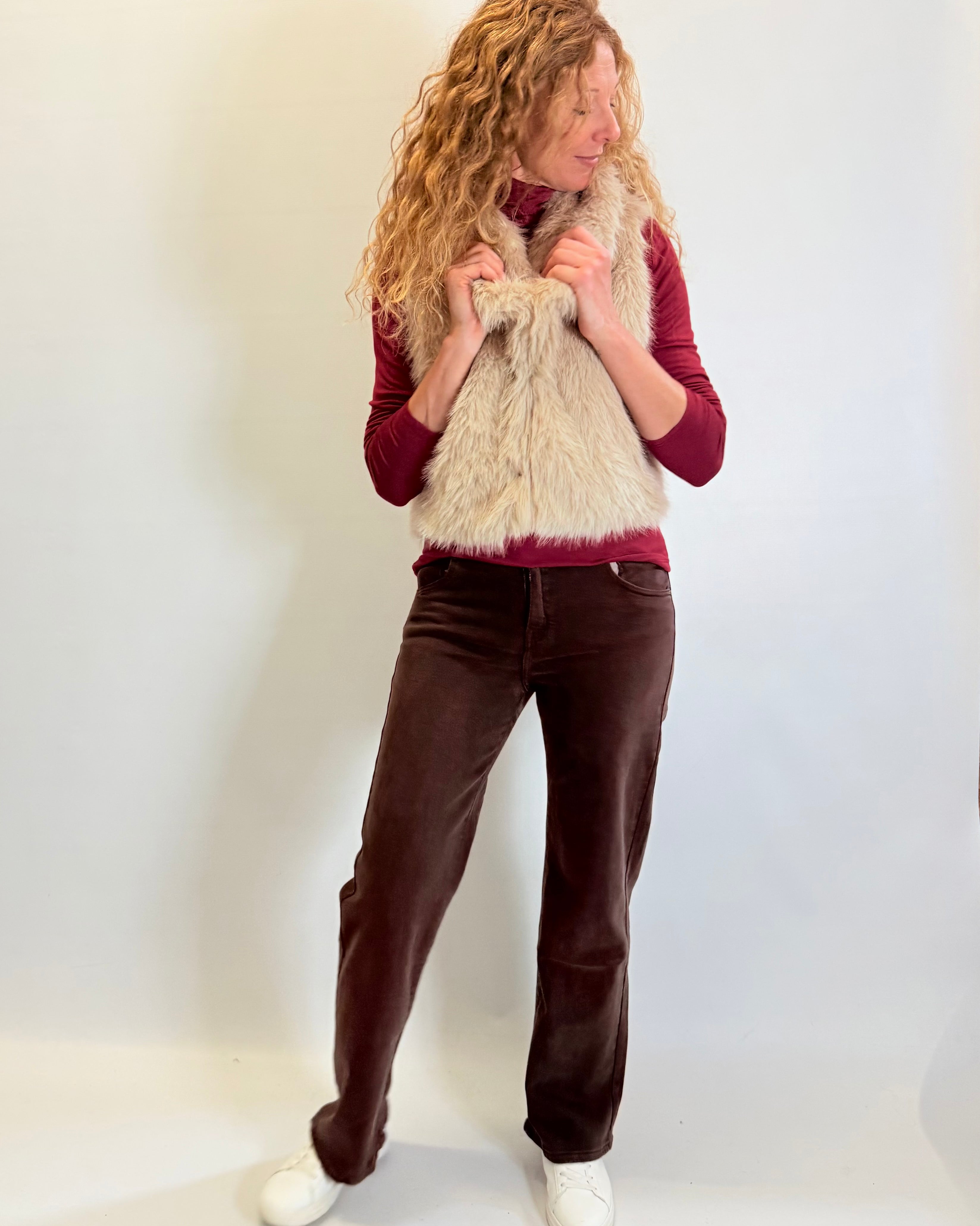 Person wearing a red sweater, brown pants, and a beige scarf against a white background