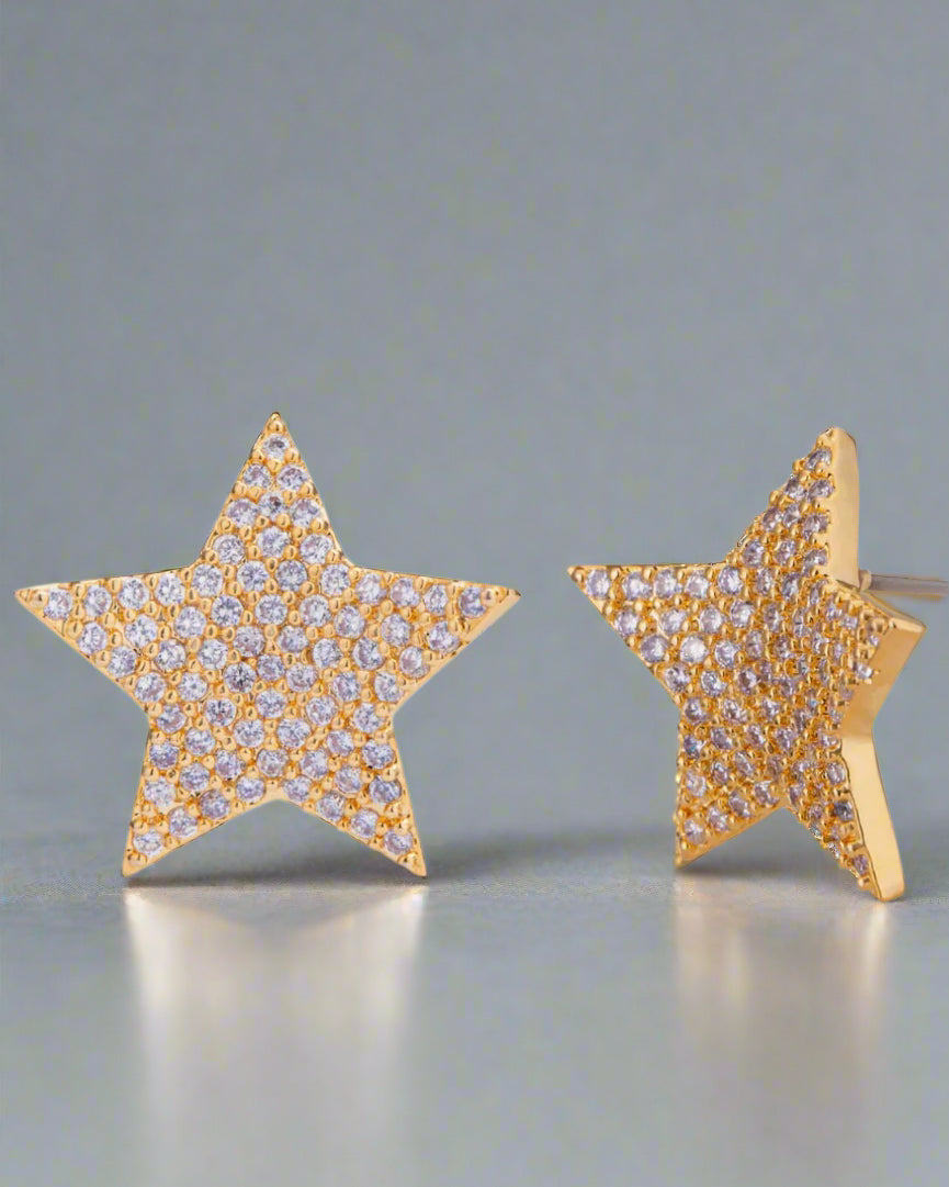 Star-shaped earrings with gold frame and clear stones on a white background