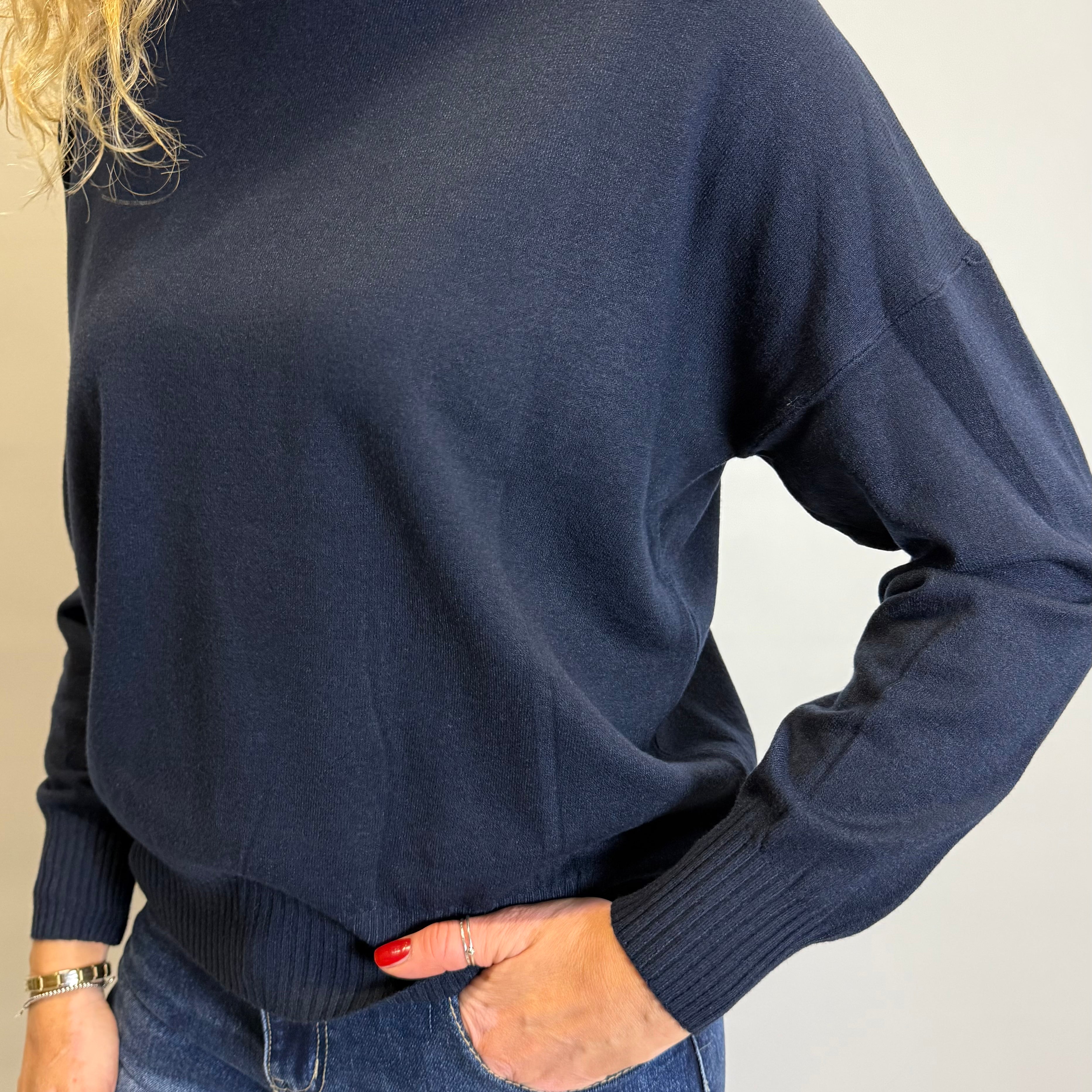 Person wearing a navy sweater and blue jeans against a plain background