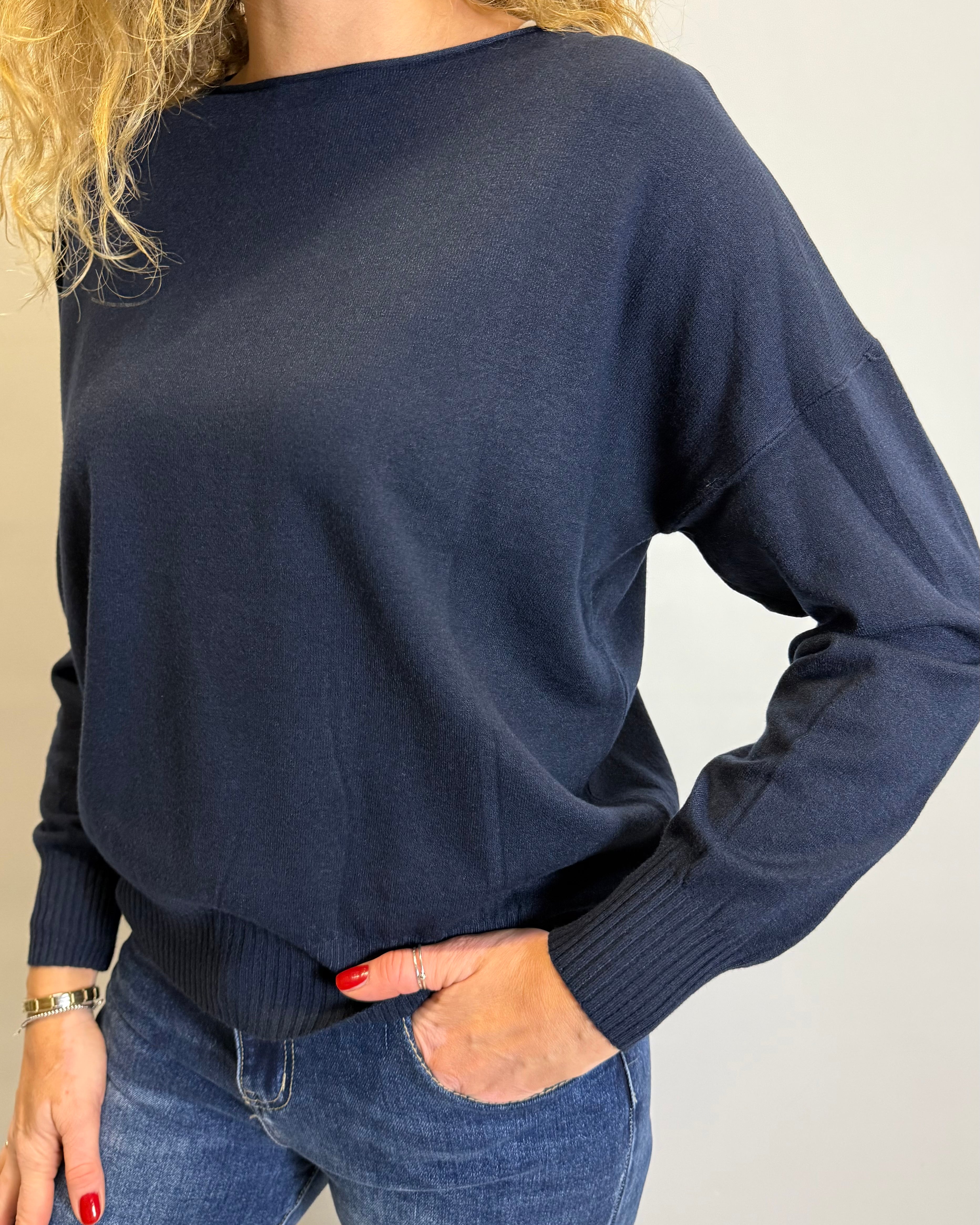 Person wearing a navy sweater and blue jeans against a plain background