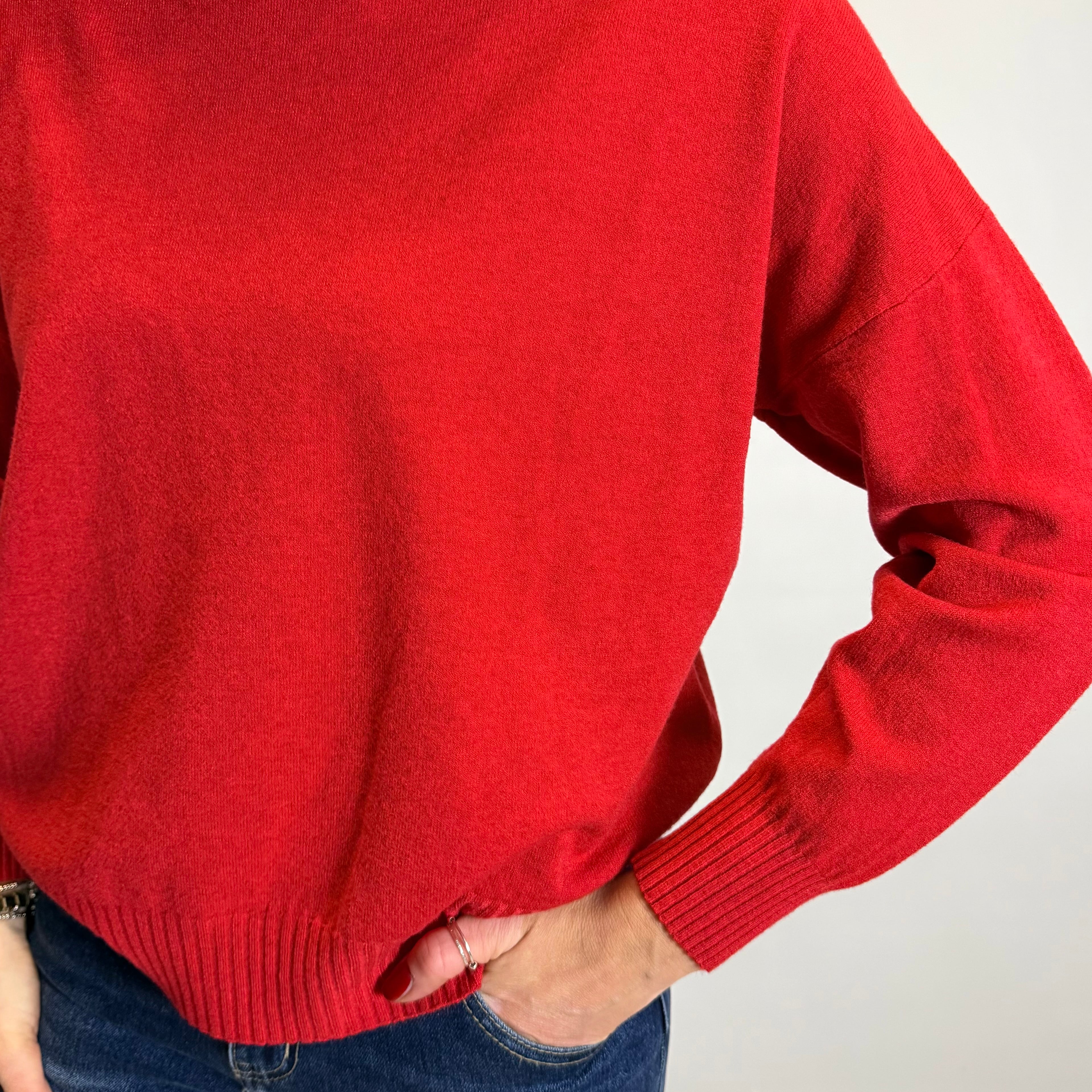 Person wearing a red sweater and blue jeans against a plain background