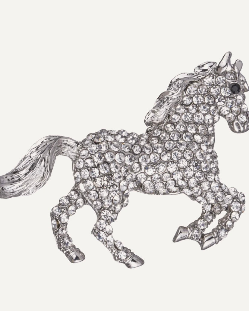 Silver horse-shaped brooch with crystal embellishments on a white background