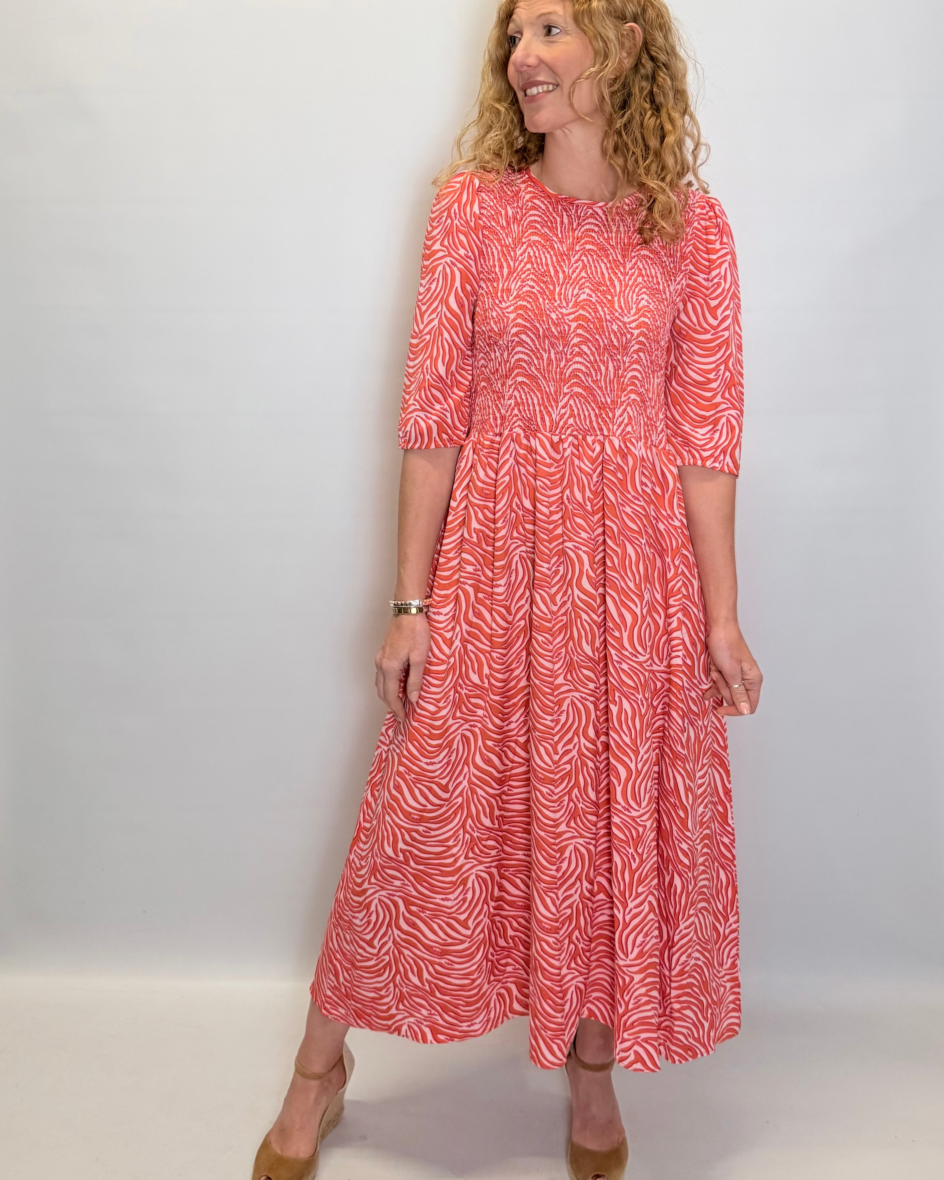 Woman wearing a red patterned dress against a white background