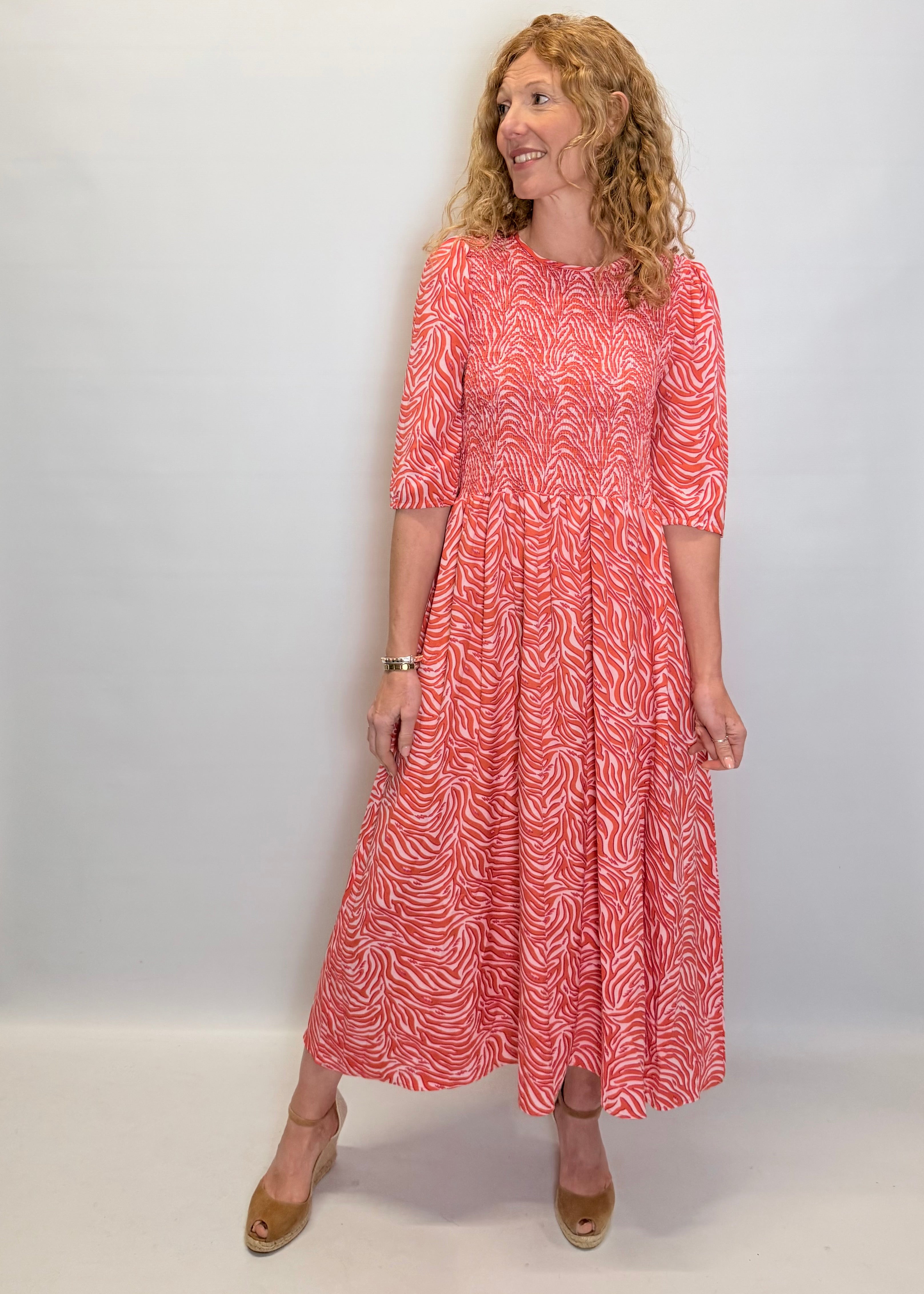 Woman wearing a red patterned dress against a white background