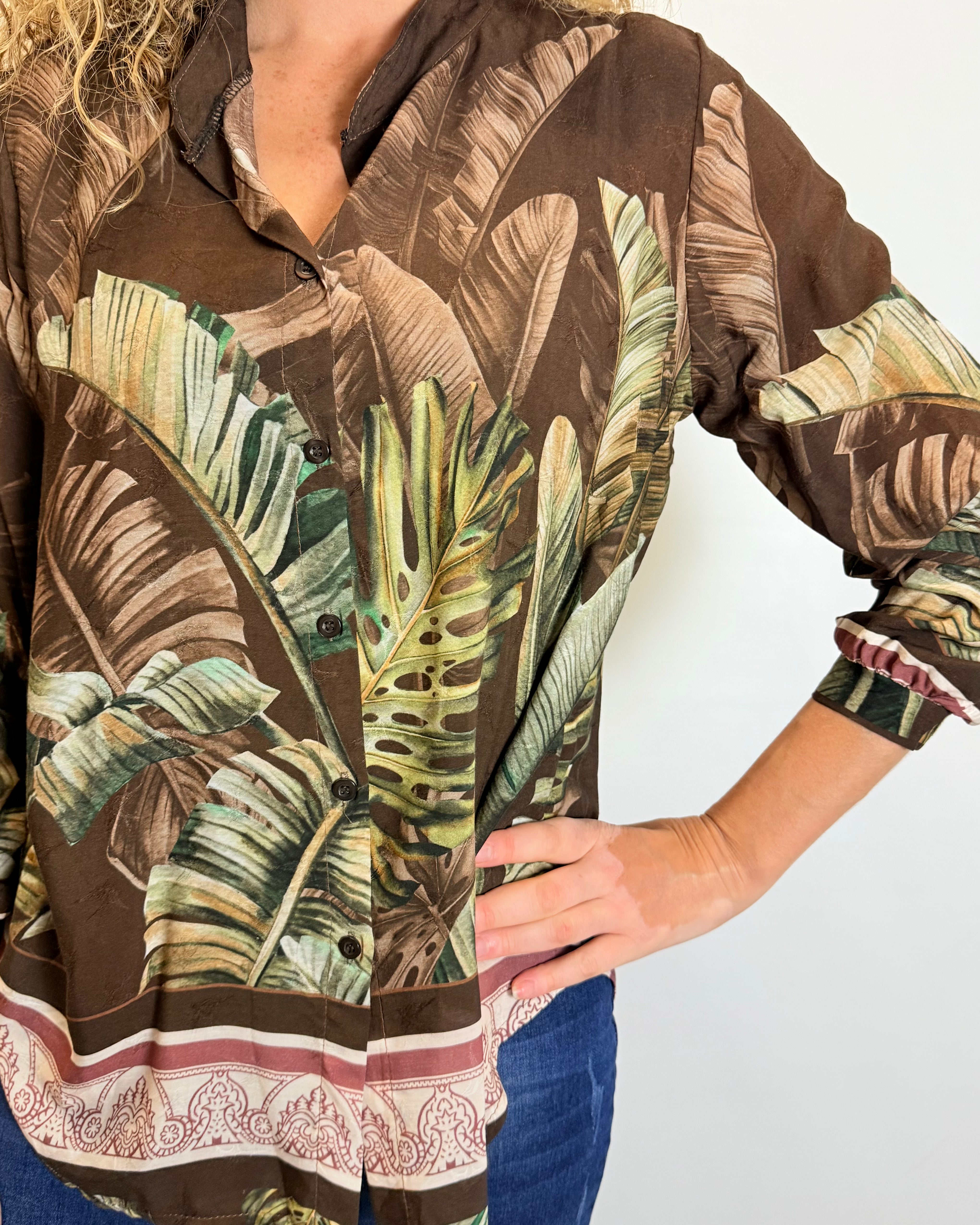 Person wearing a brown shirt with tropical leaf pattern on a plain background