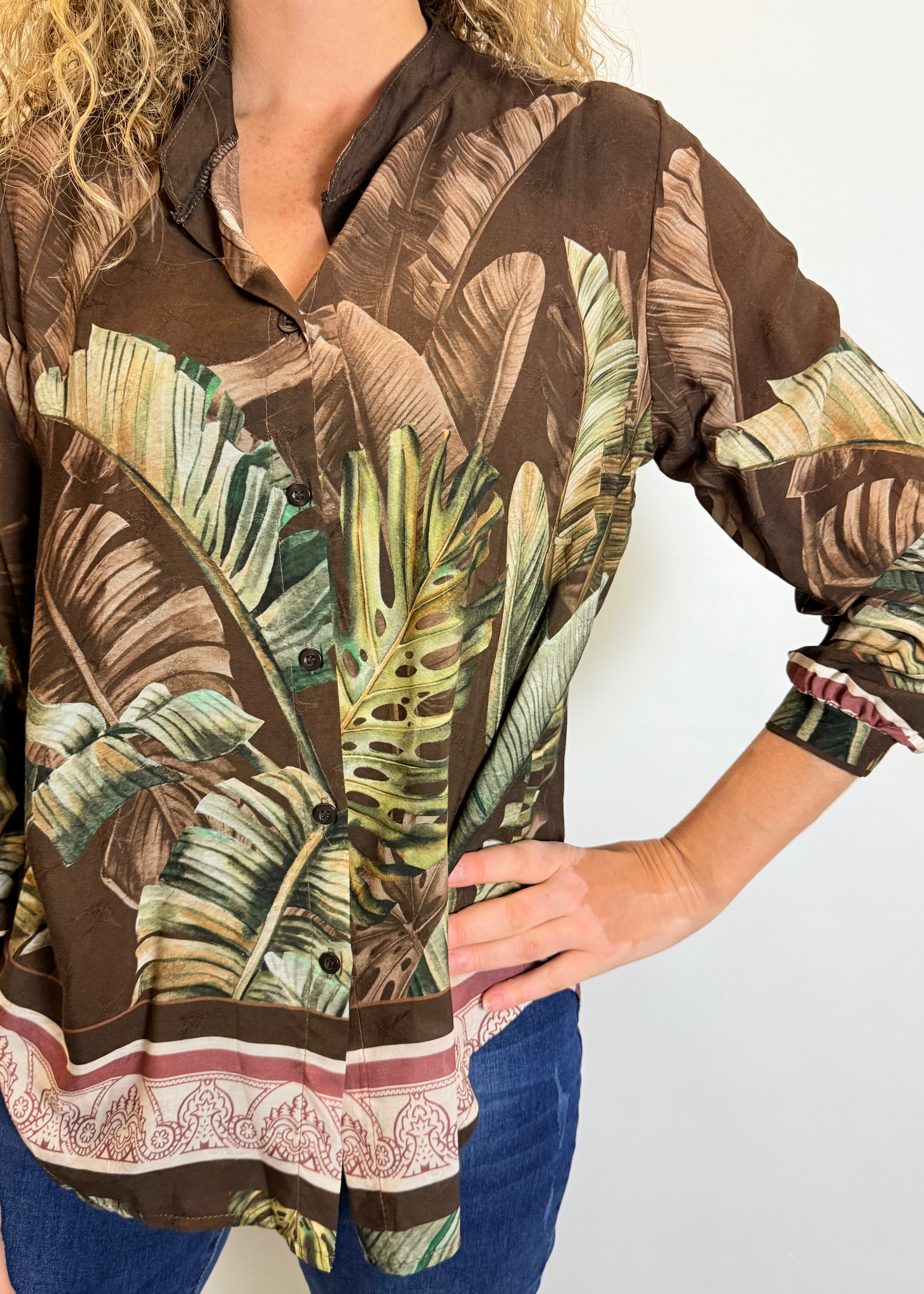 Person wearing a brown shirt with tropical leaf pattern on a plain background