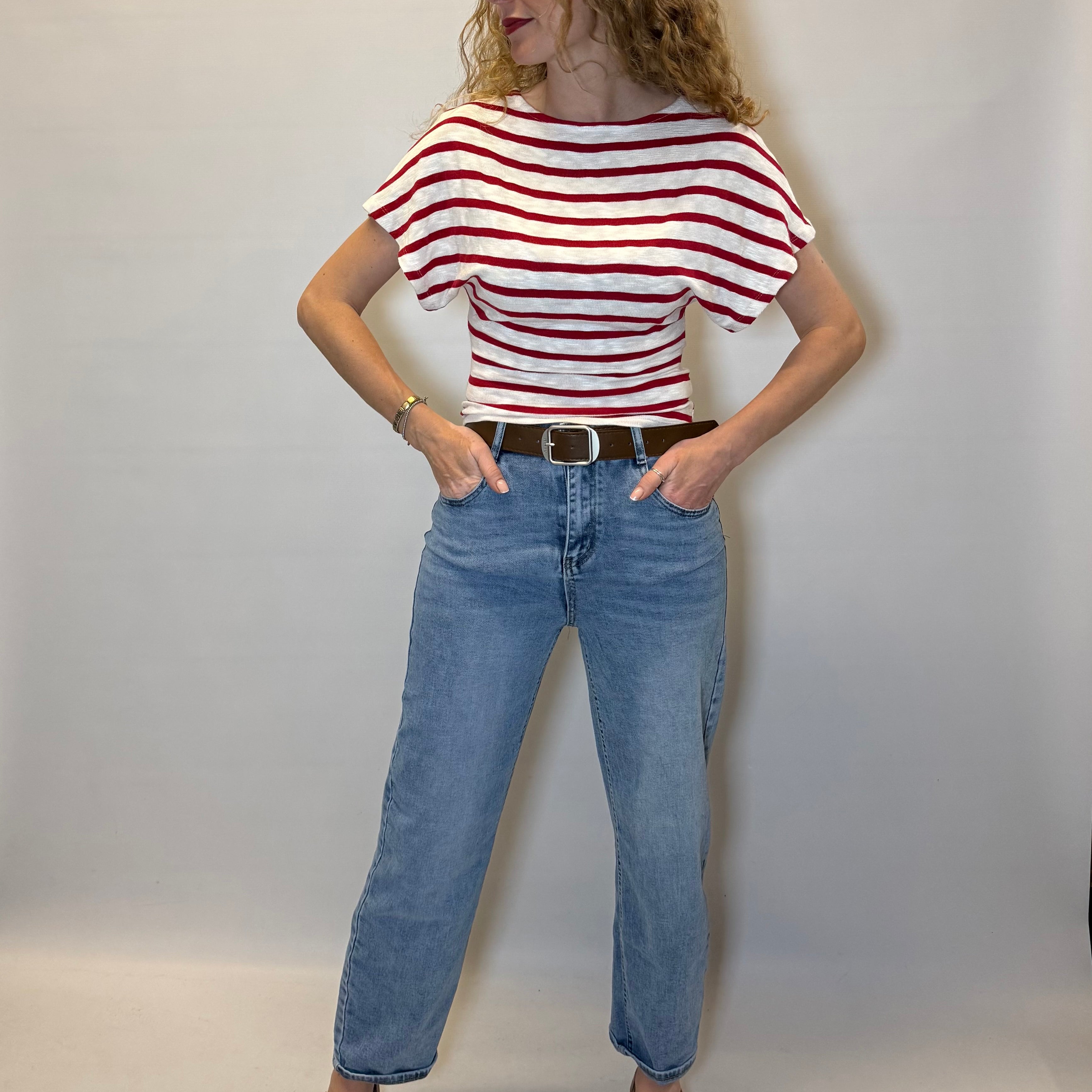 Person wearing a red and white striped shirt and blue jeans against a plain background