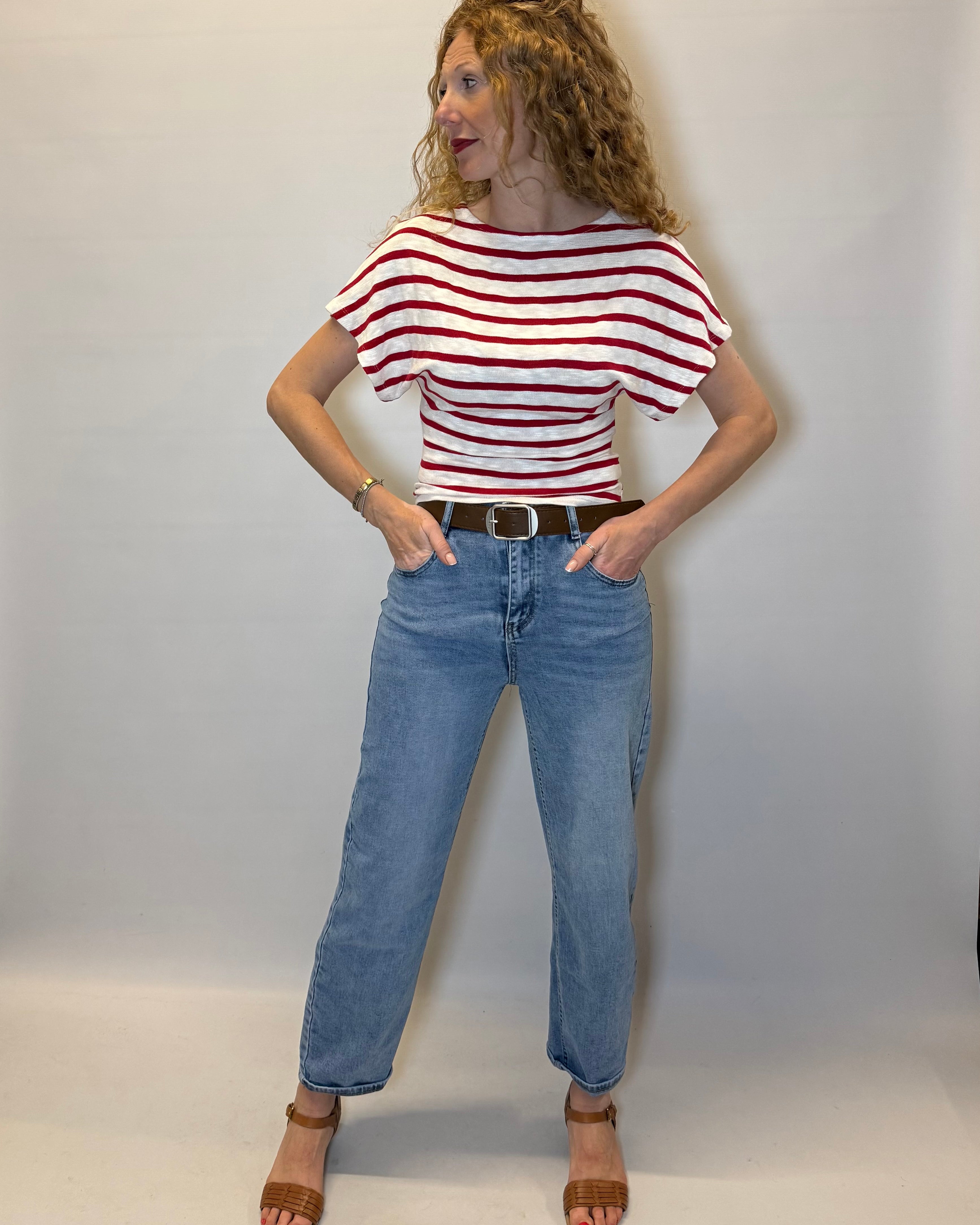 Person wearing a red and white striped shirt and blue jeans against a plain background