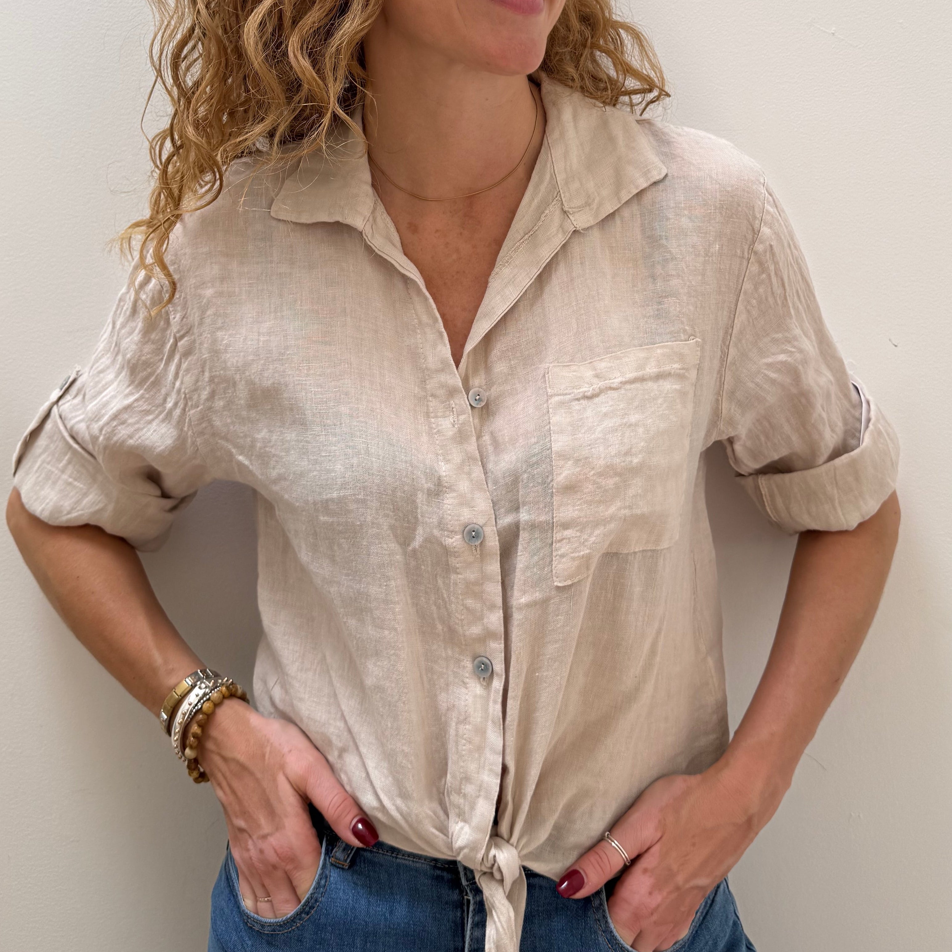 Woman wearing a beige blouse and blue jeans against a white background