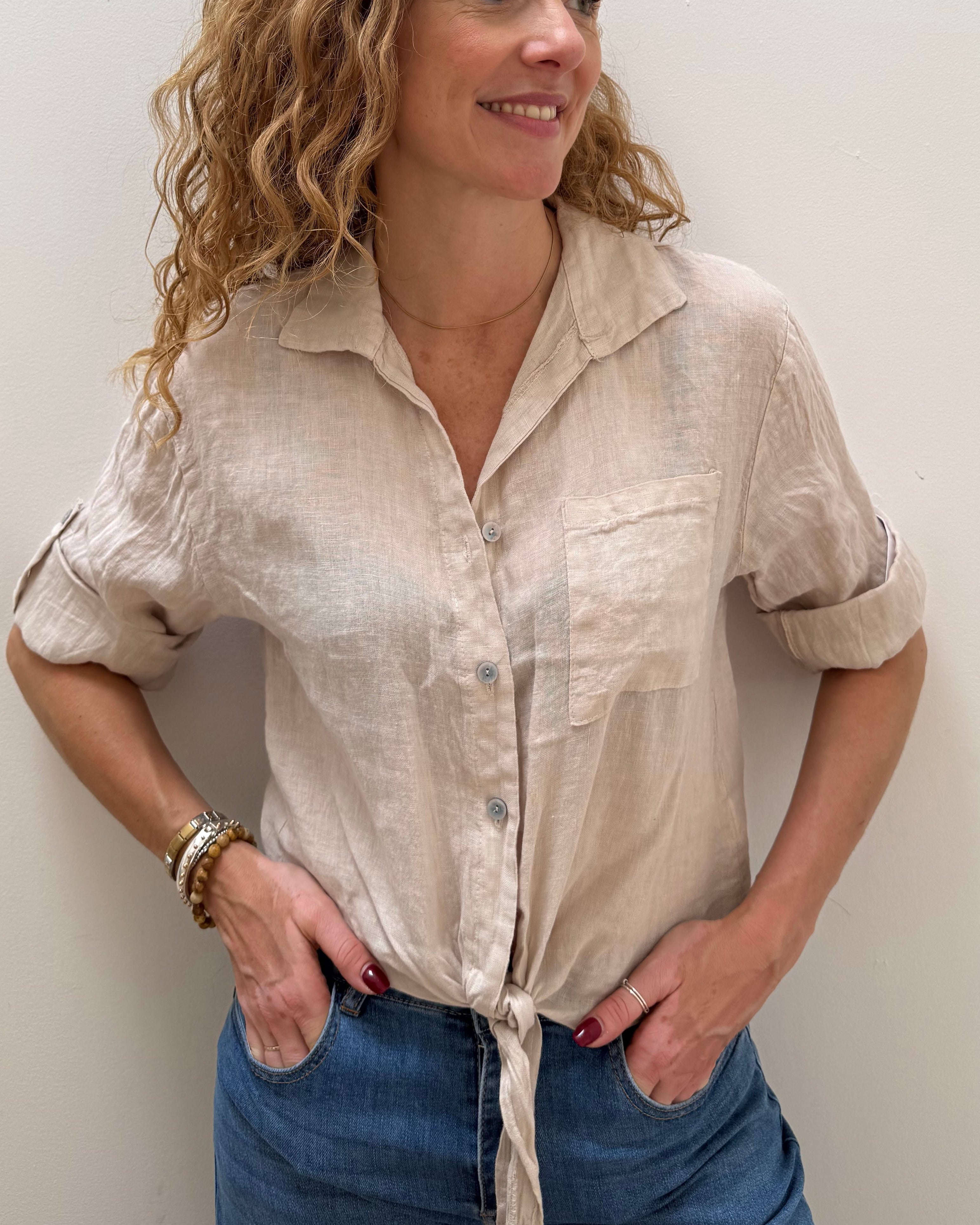 Woman wearing a beige blouse and blue jeans against a white background
