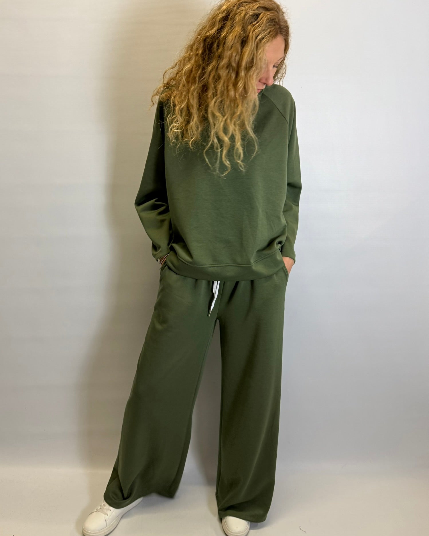 Person wearing a green tracksuit against a white background