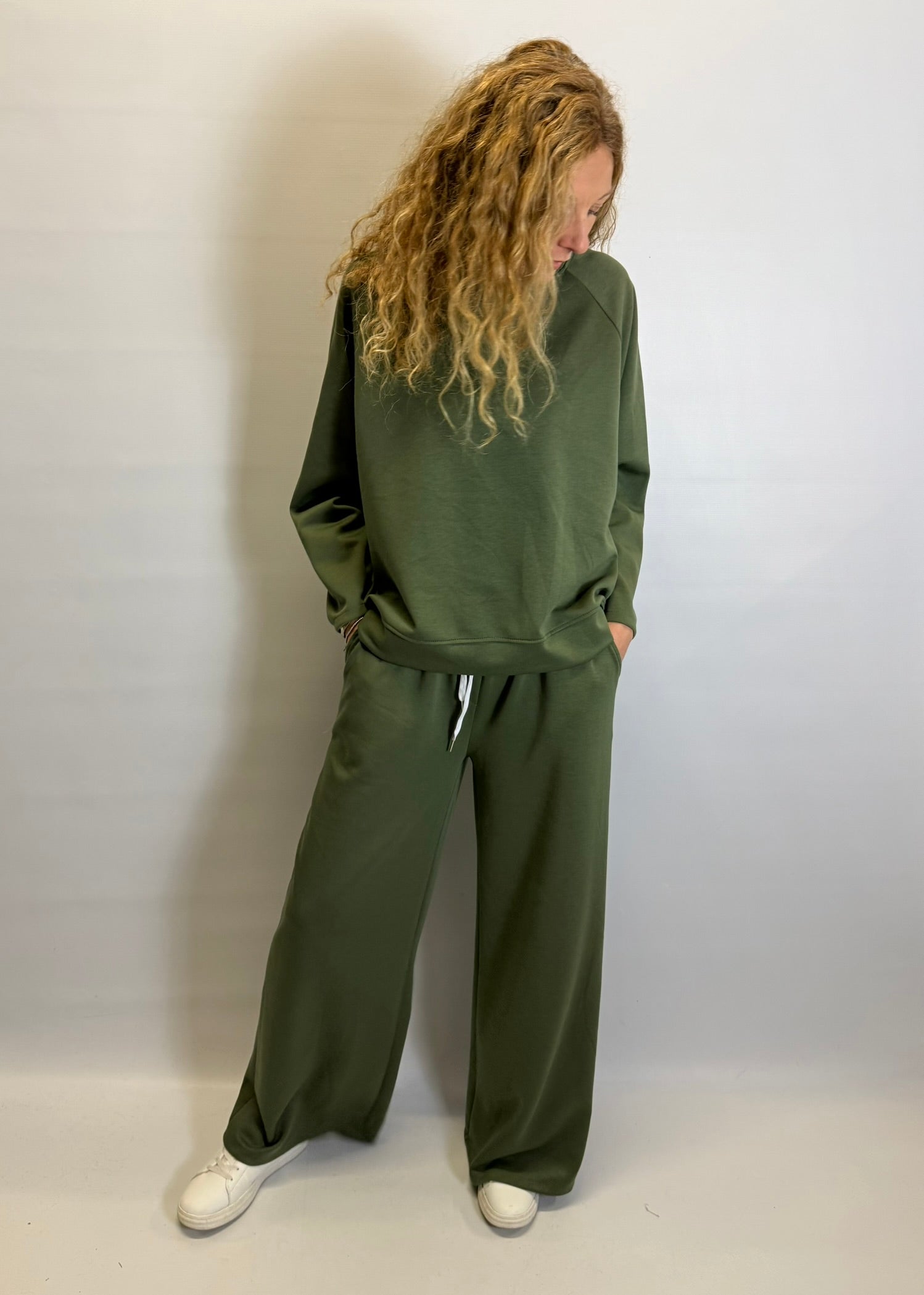 Person wearing a green tracksuit against a white background