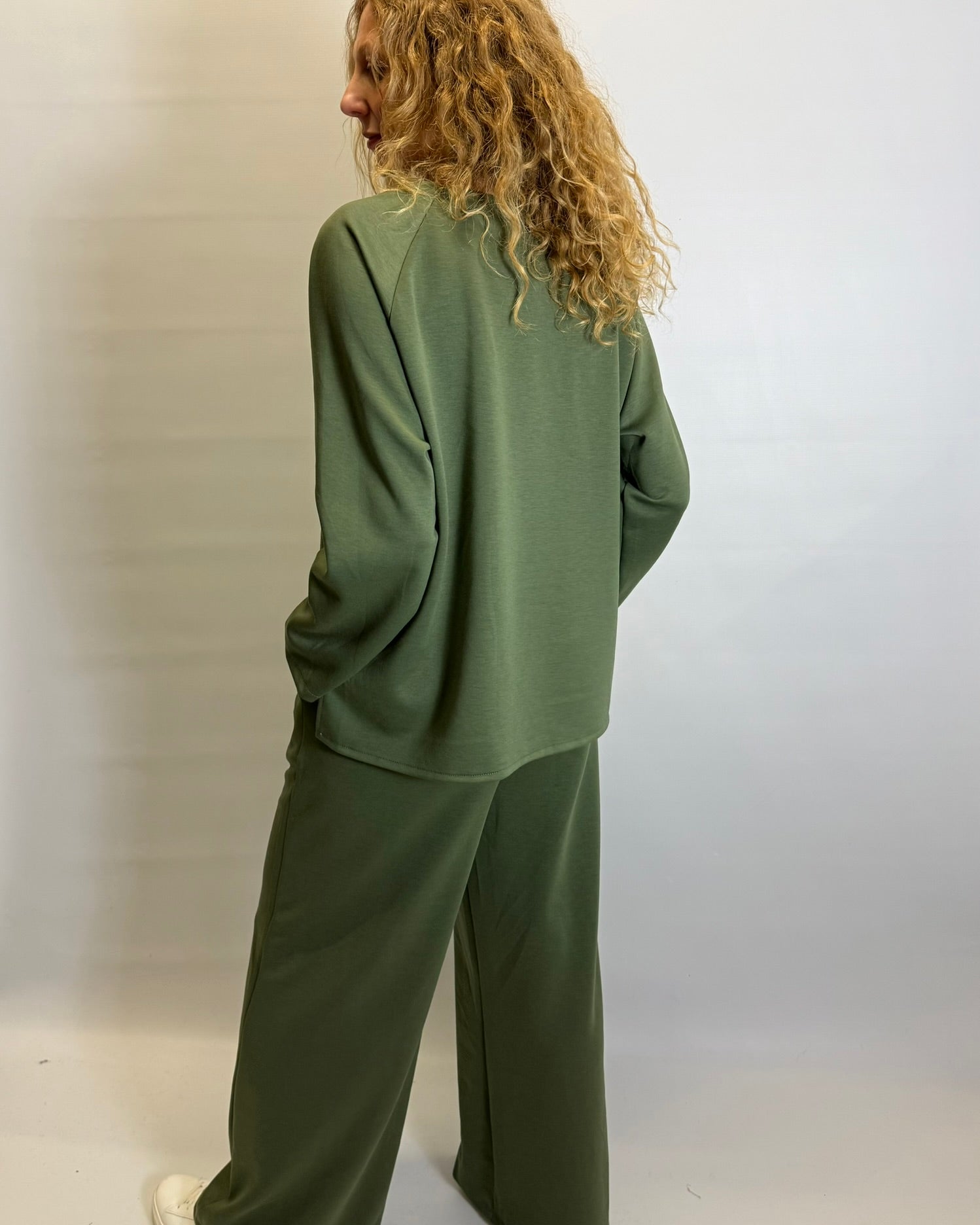 Person wearing a green tracksuit against a plain background