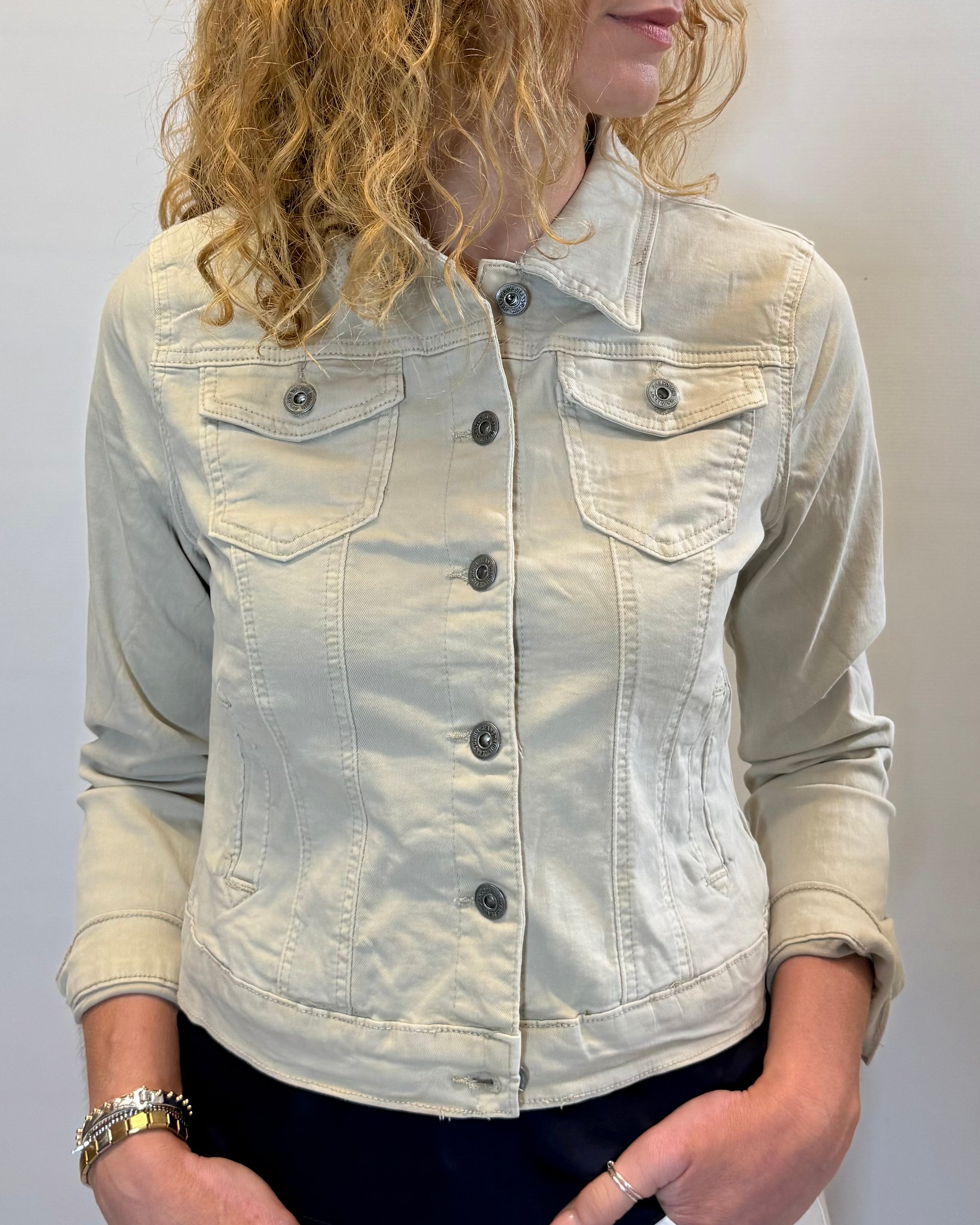 Person wearing a light-colored denim jacket against a plain background