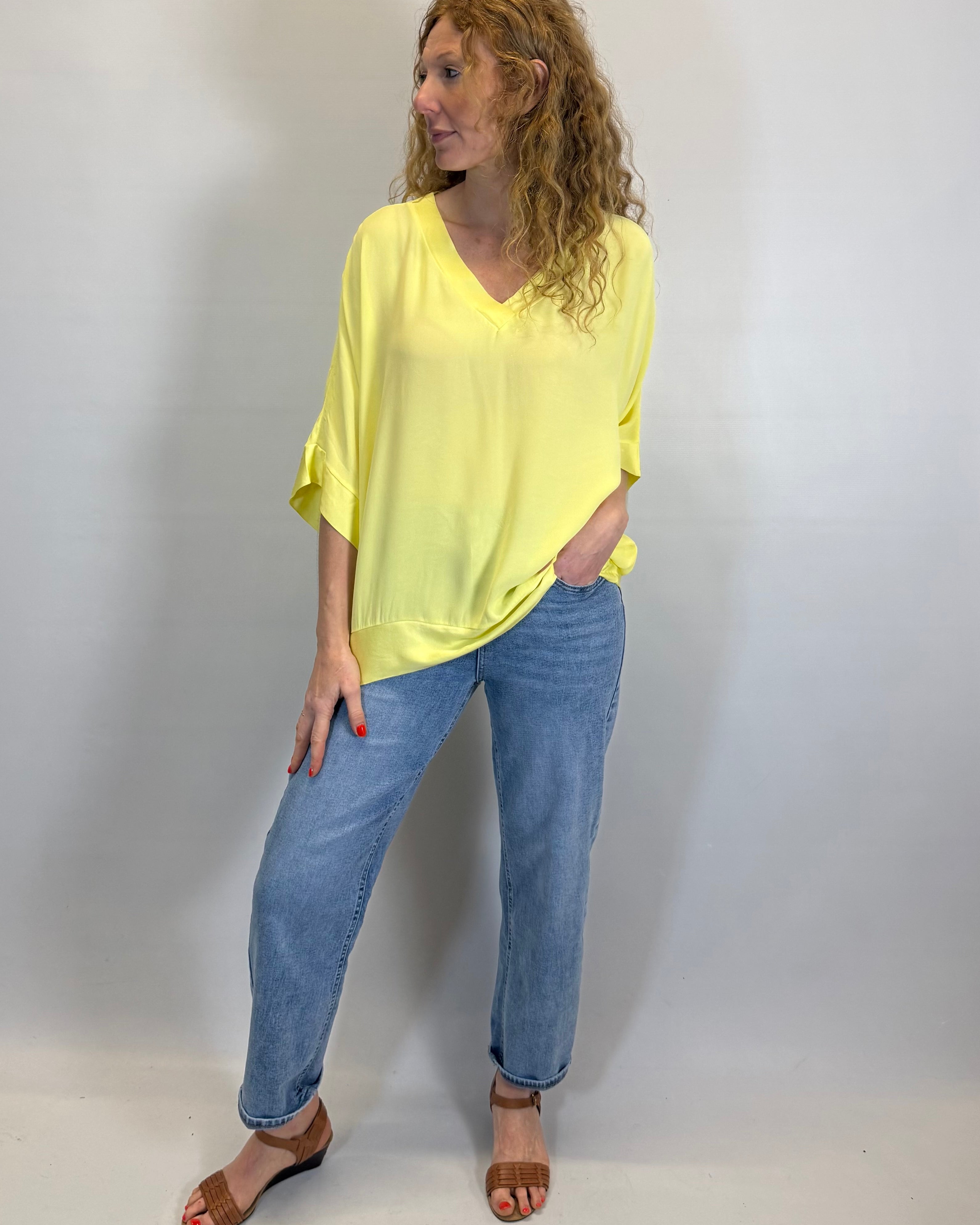 Woman wearing a yellow top and blue jeans against a white background