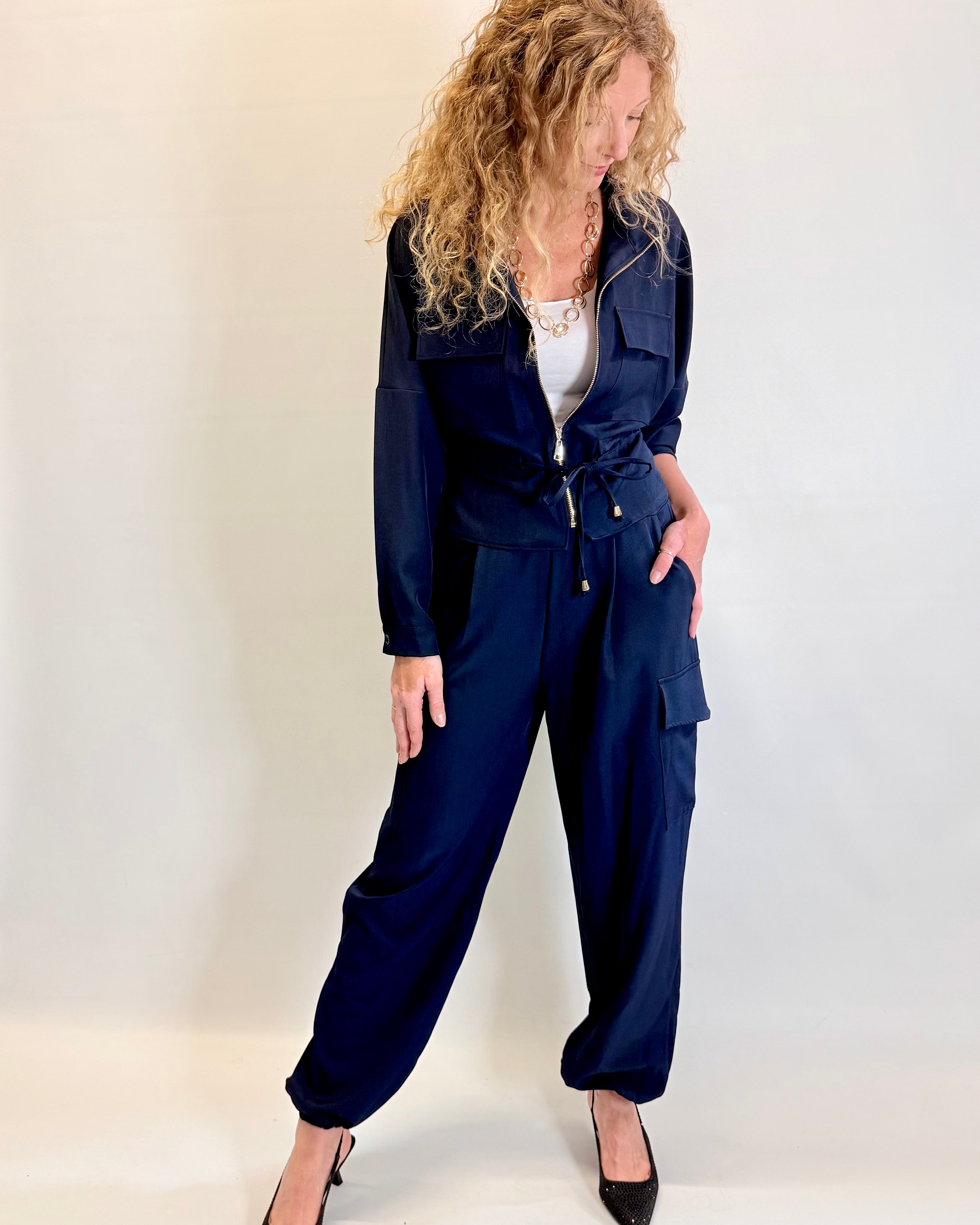 Woman wearing a navy blue jumpsuit against a white background