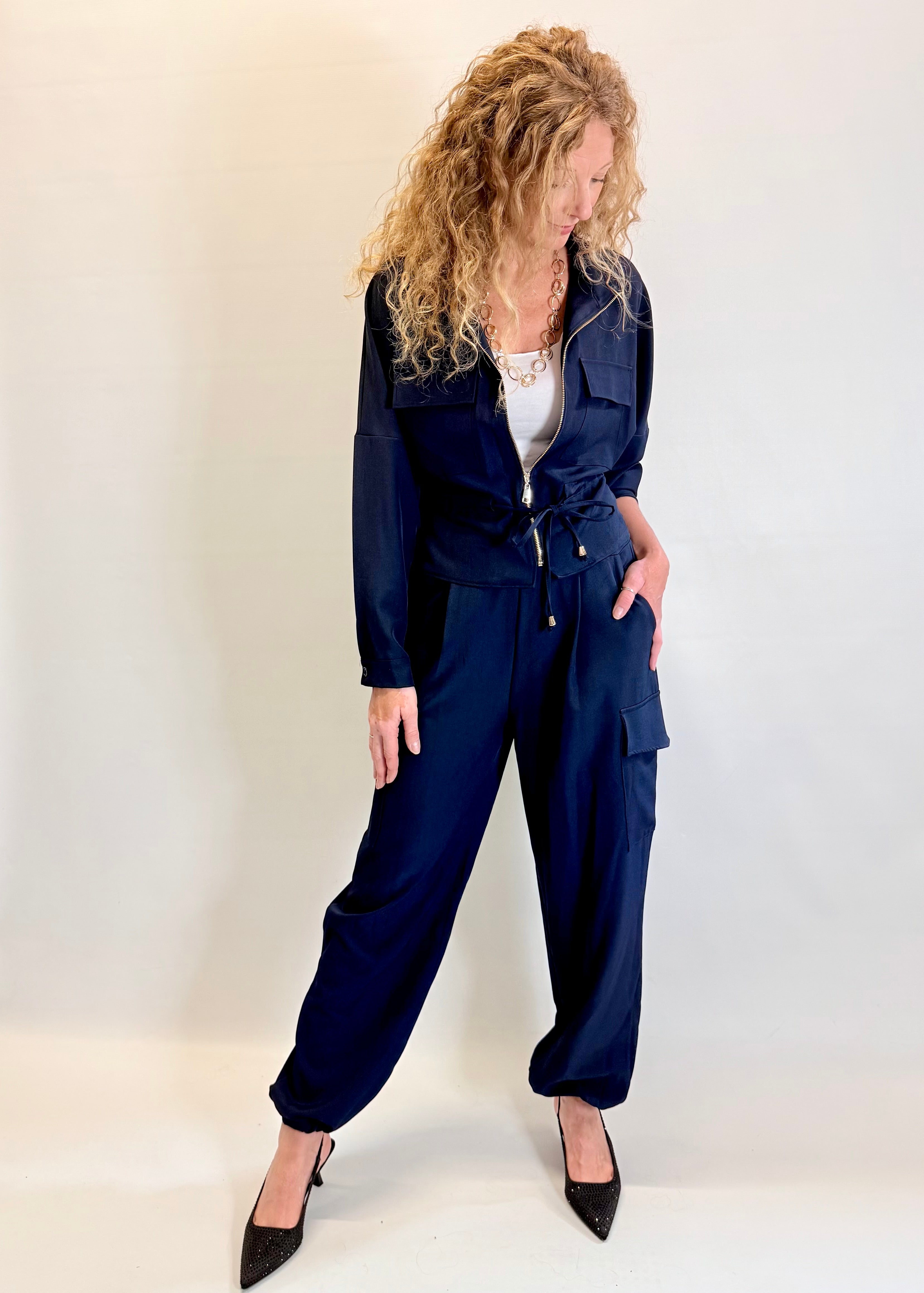 Woman wearing a navy blue jumpsuit against a white background