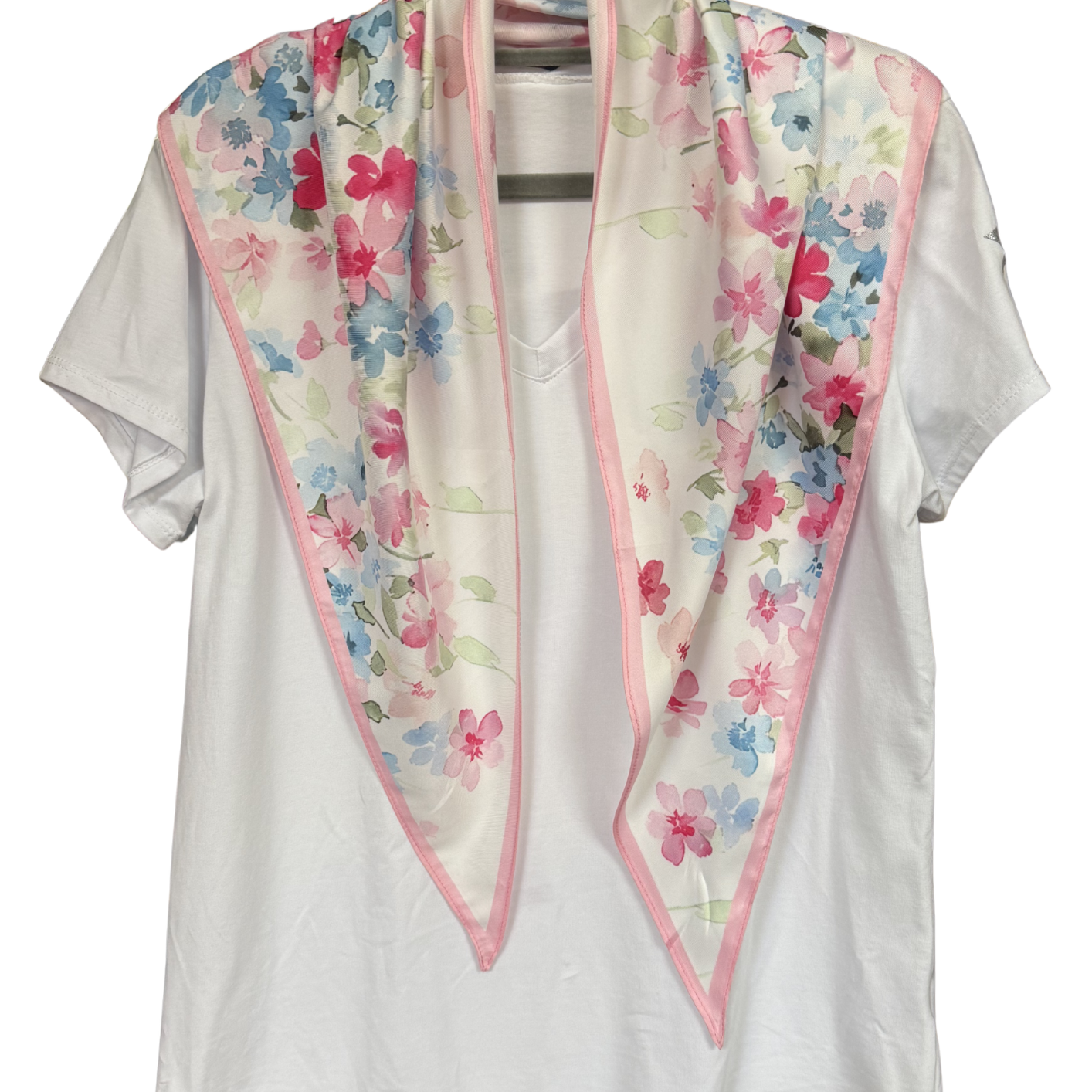 White blouse with a floral scarf draped over it on a hanger