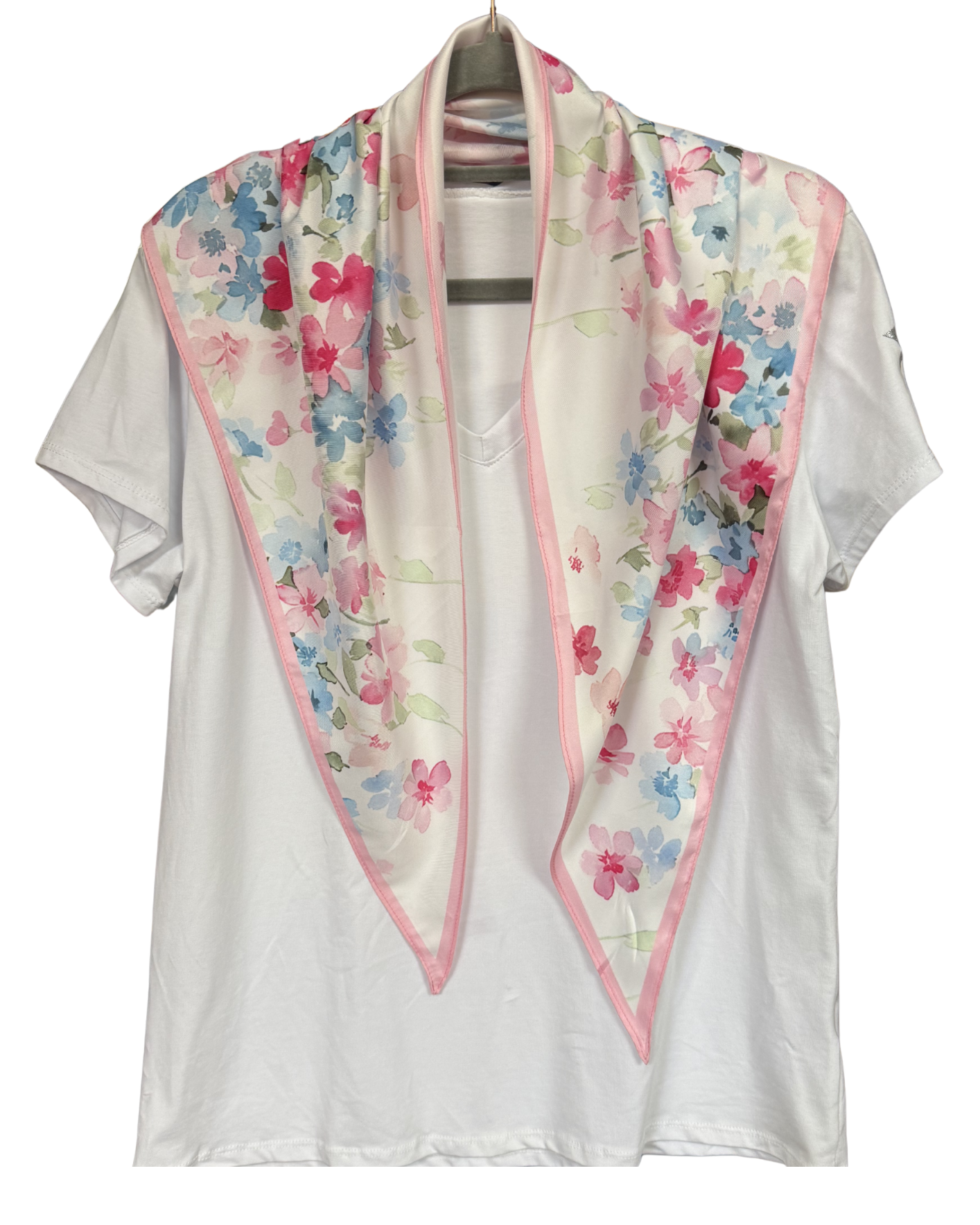 White blouse with a floral scarf draped over it on a hanger