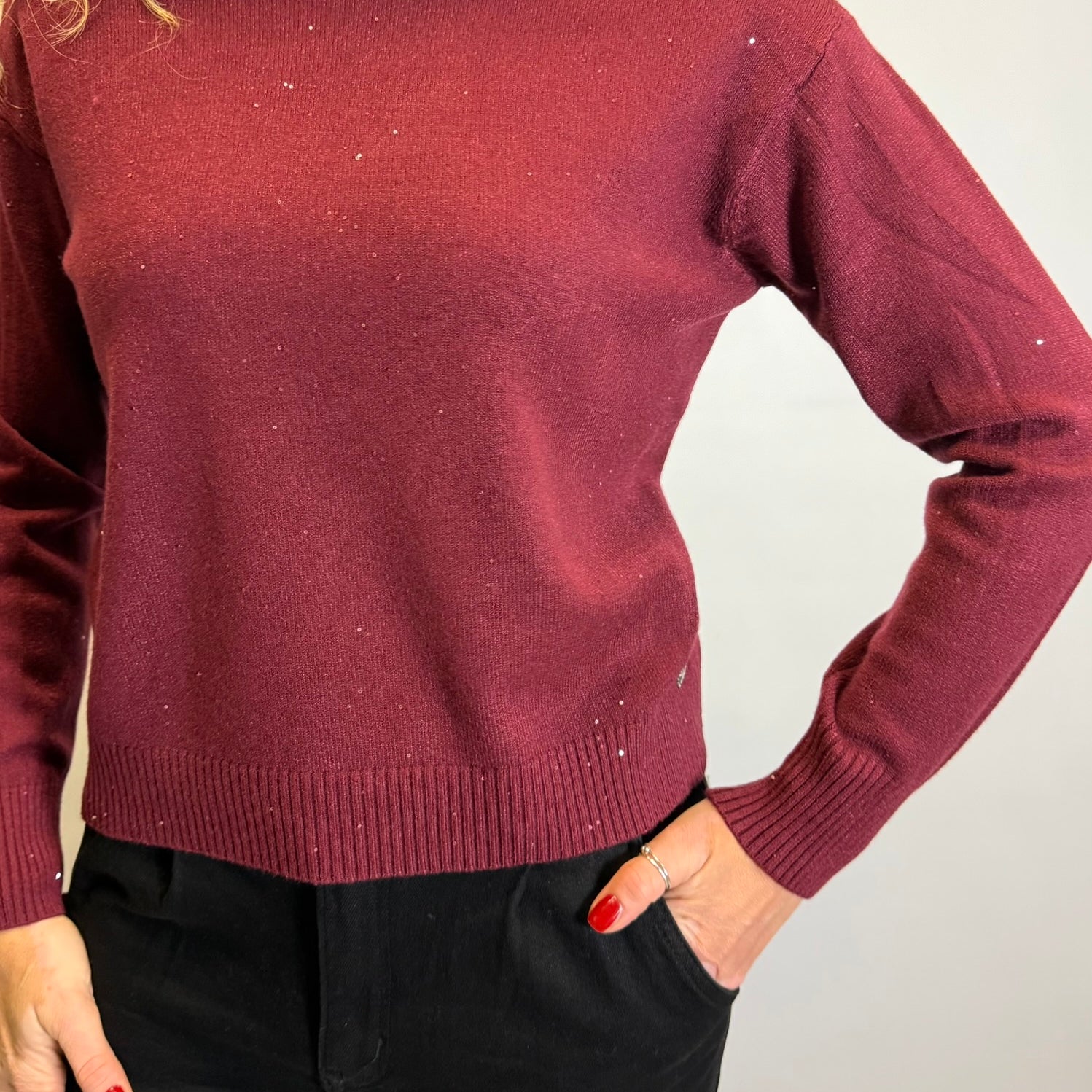 Maroon sweater worn by a person on a plain background