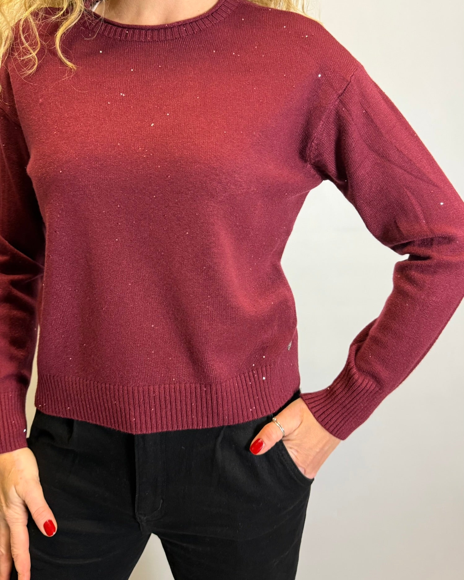 Maroon sweater worn by a person on a plain background