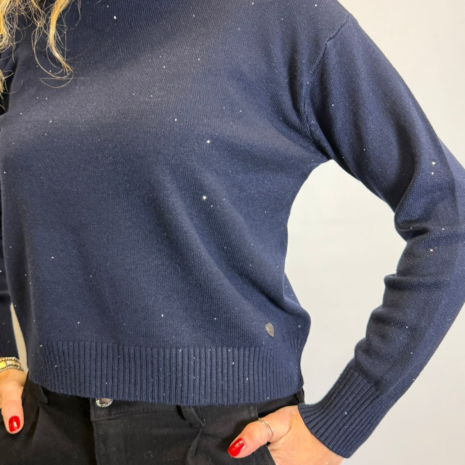 Navy blue sweater worn by a person on a plain background