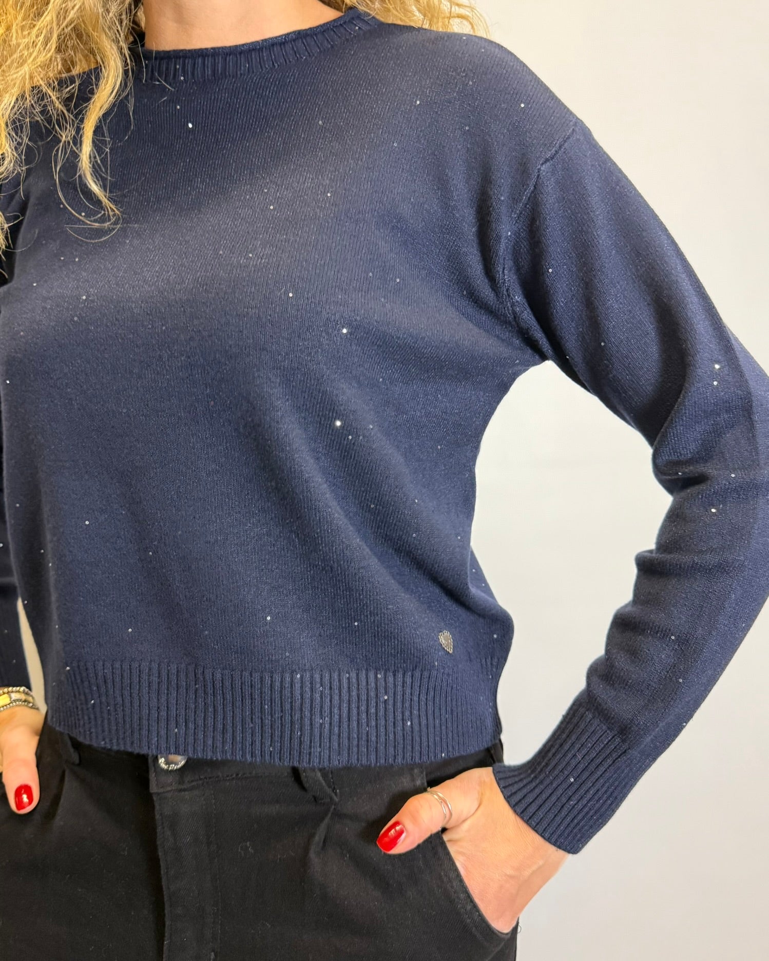 Navy blue sweater worn by a person on a plain background