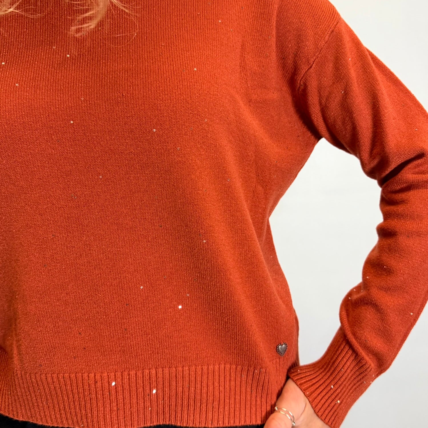Person wearing a rust-colored sweater against a white background