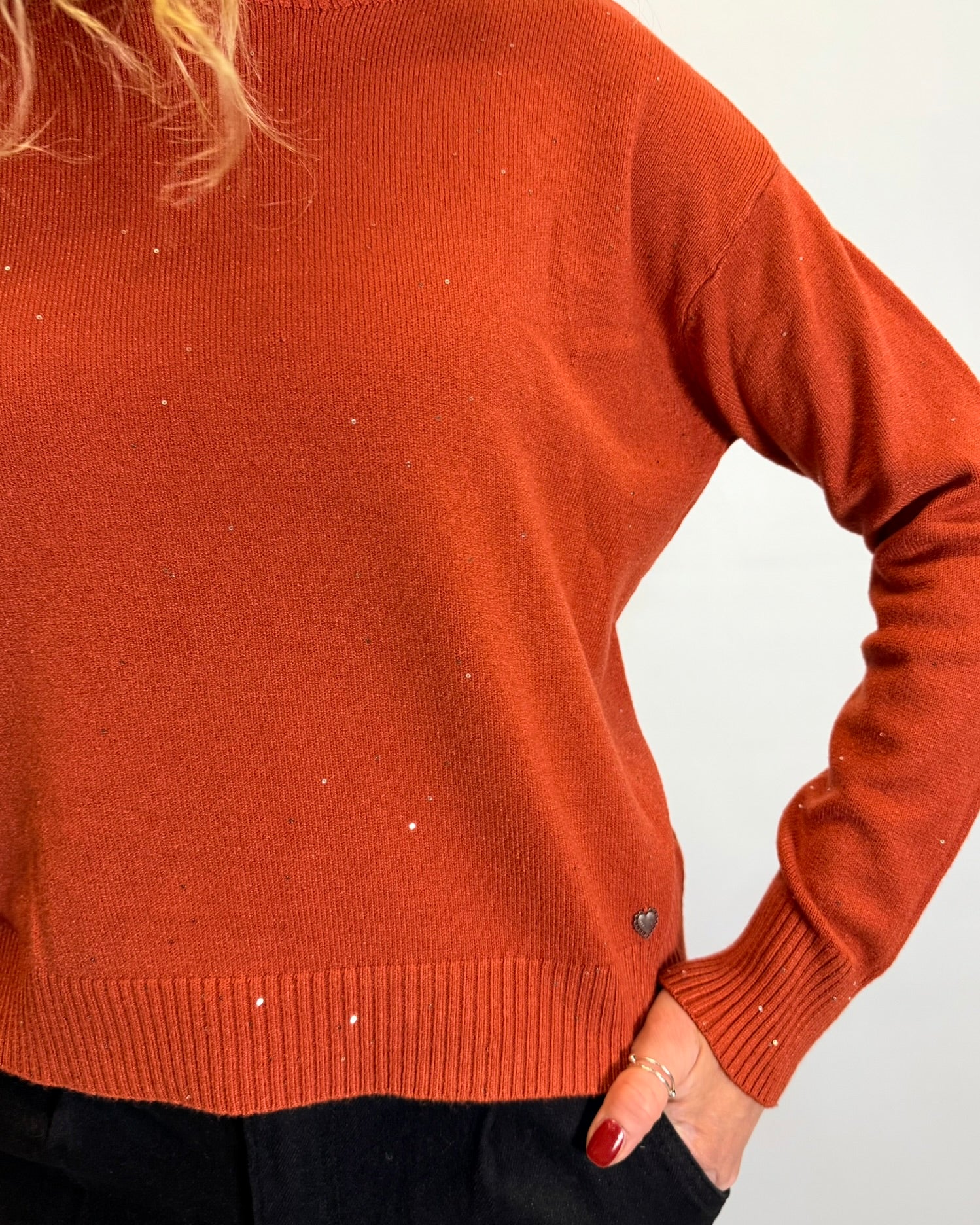 Person wearing a rust-colored sweater against a white background