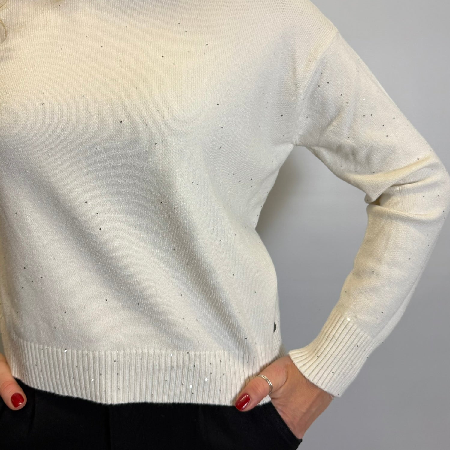 White sweater worn by a person with a plain background